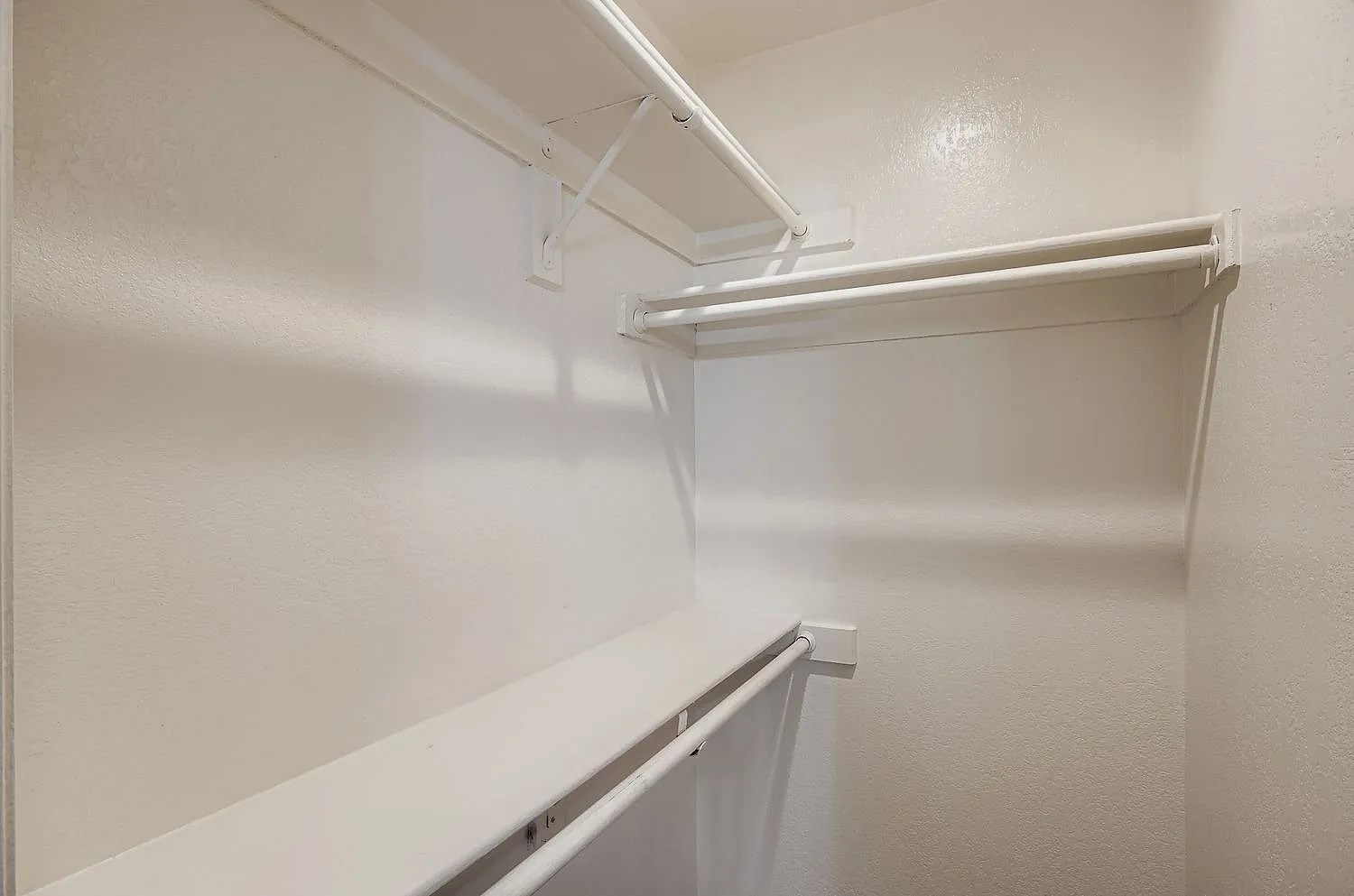 Walk-in closet, white shelving, metal rods, recessed lighting