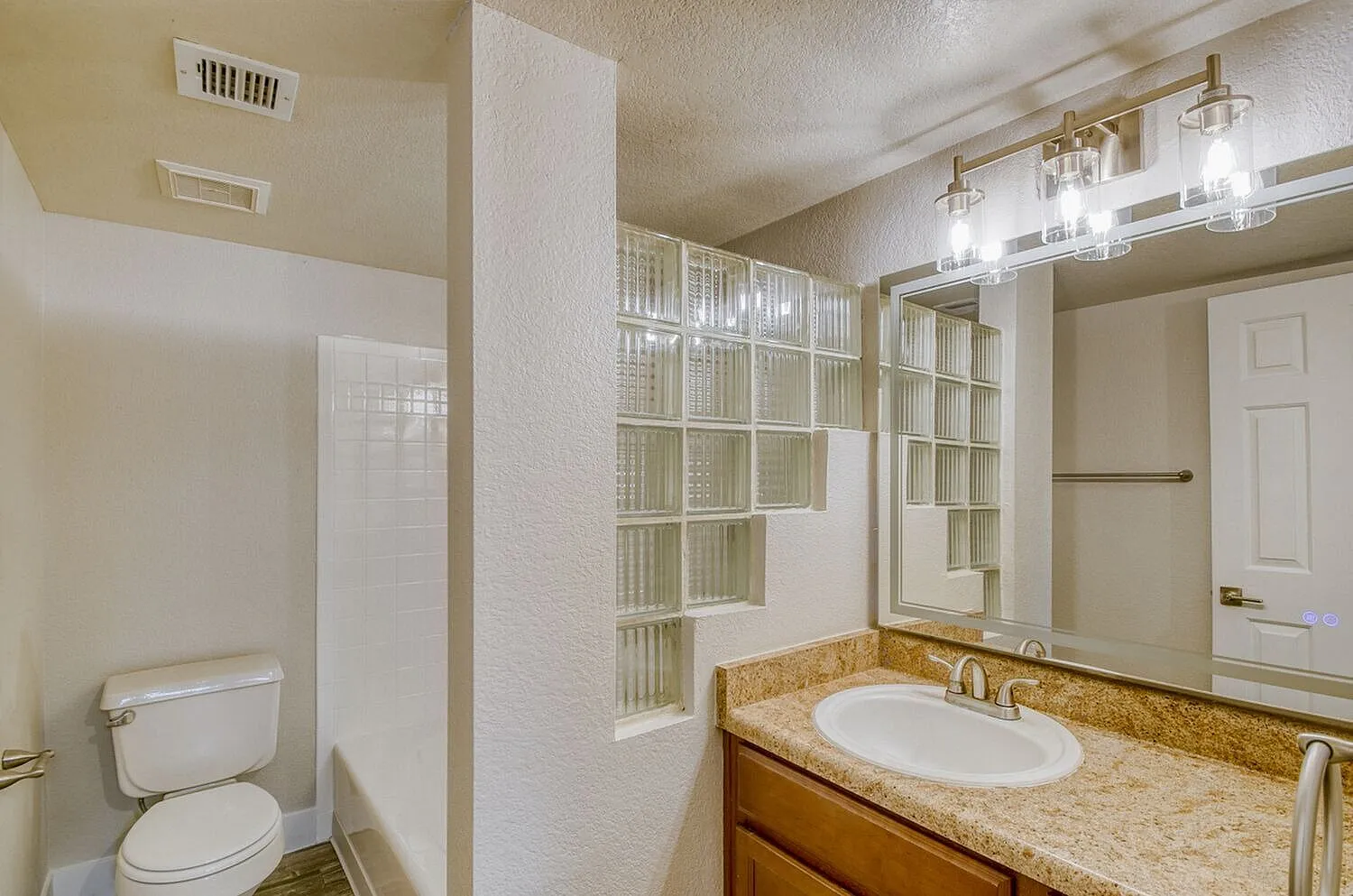 Primary bathroom, granite countertops, white cabinetry, framed mirror, glass shower enclosure