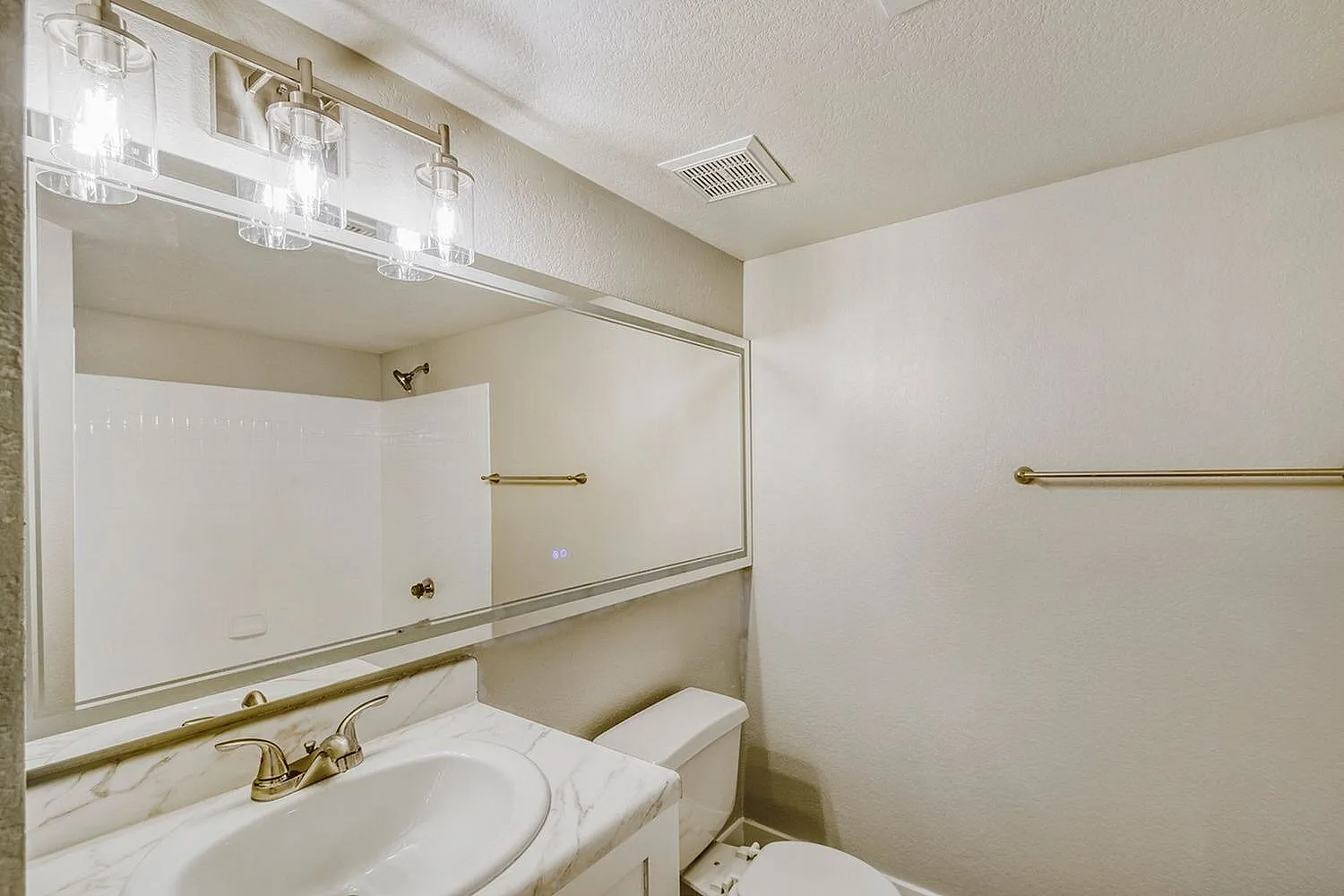 Primary bathroom, white vanity, framed mirror, brass fixtures, marble countertop