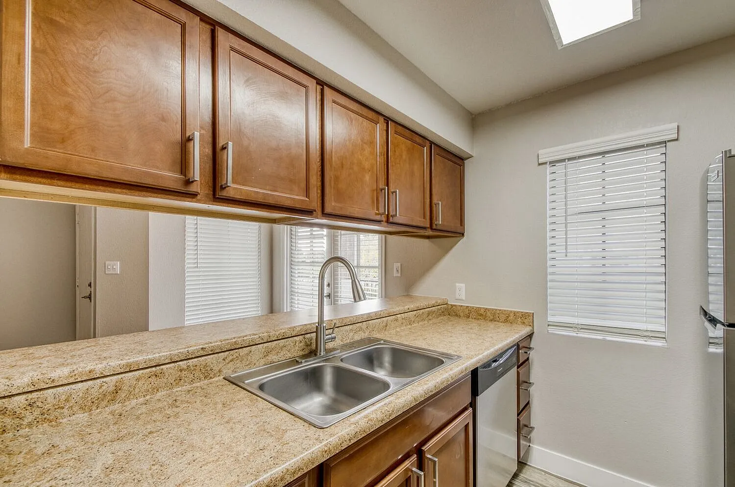 Kitchen, wood cabinetry, granite countertops, stainless sink, white blinds