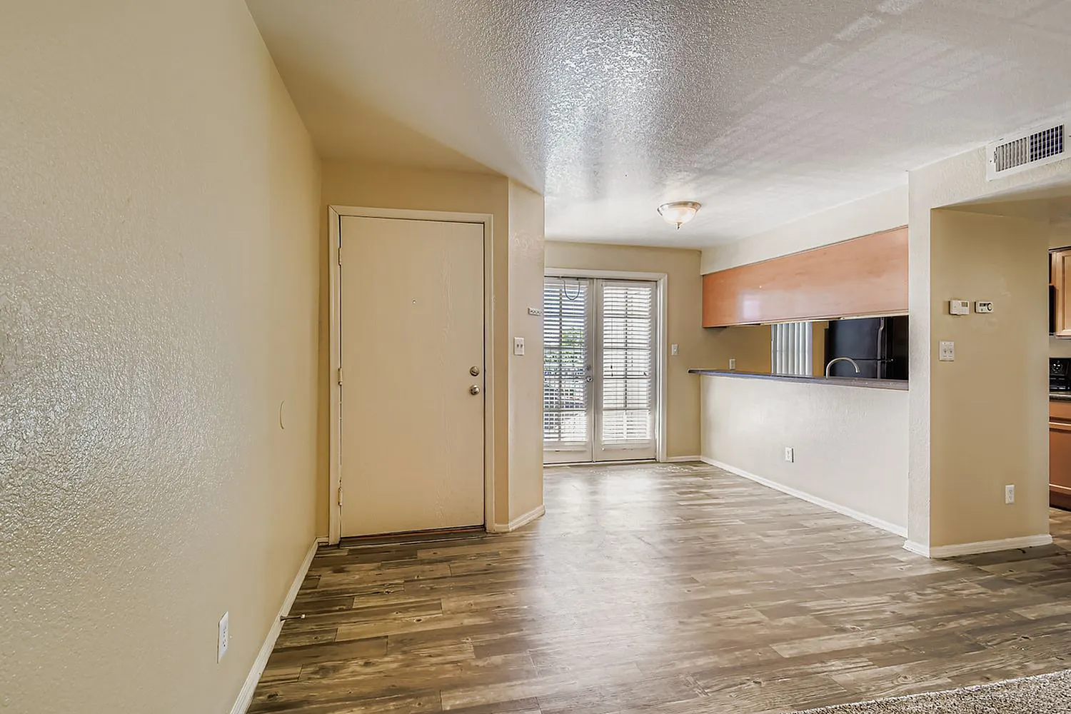 Entryway, wood-style plank flooring, textured walls, door to patio, open living space