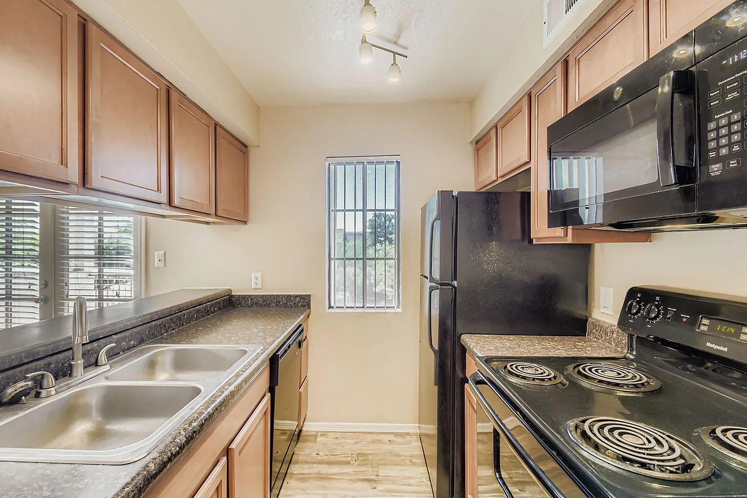 Kitchen, wood cabinetry, granite countertops, black appliances, wood-style plank flooring