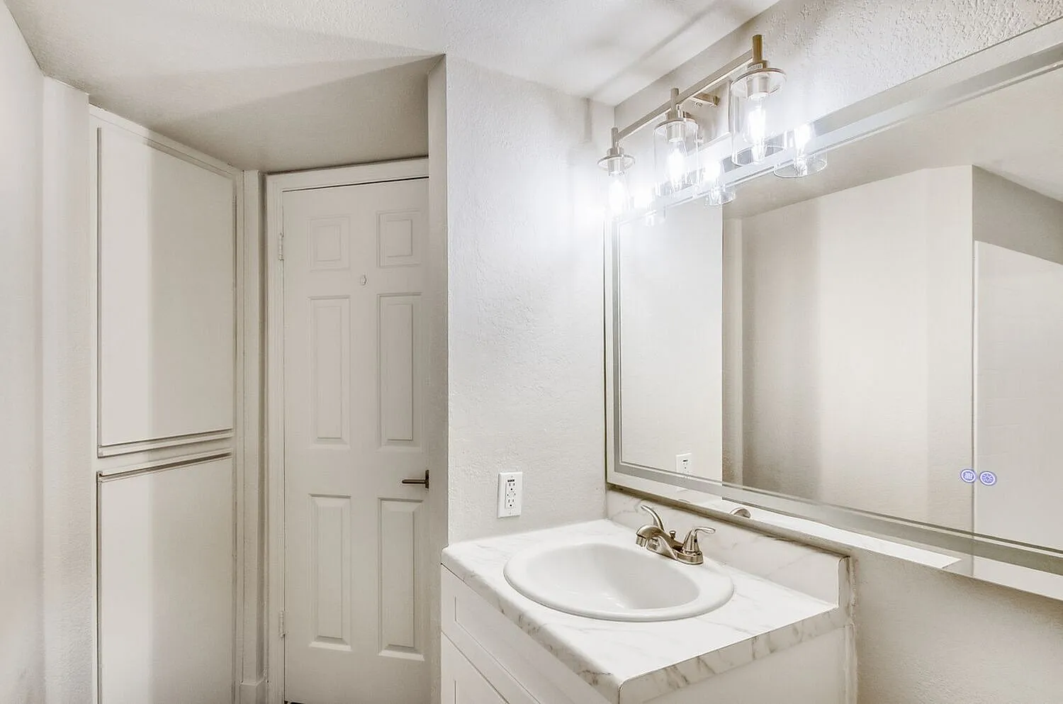 Bathroom, white vanity sink, large framed mirror, brushed nickel fixtures, overhead lighting