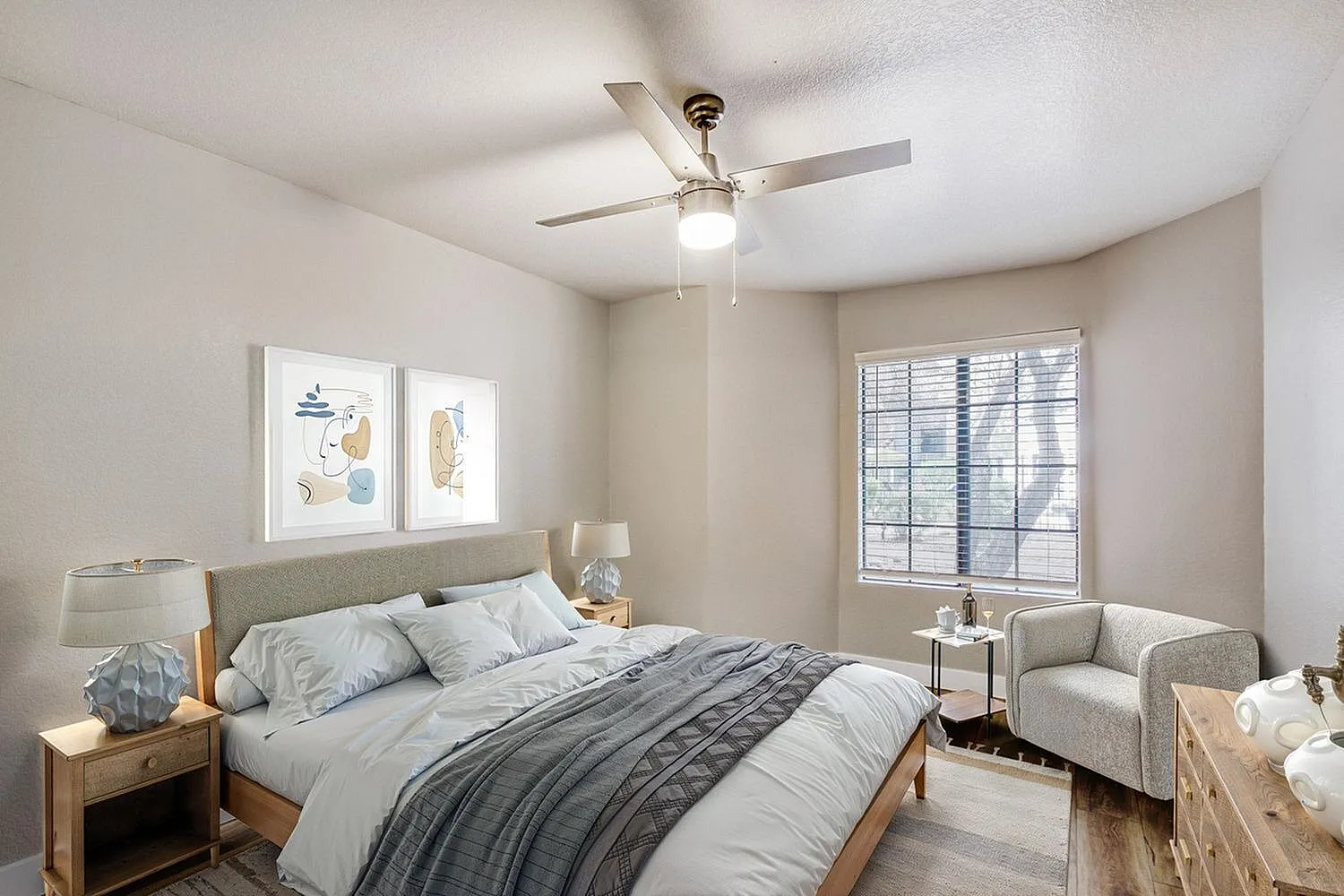 Primary bedroom, wood-style plank flooring, ceiling fan with light, upholstered headboard, bedside tables