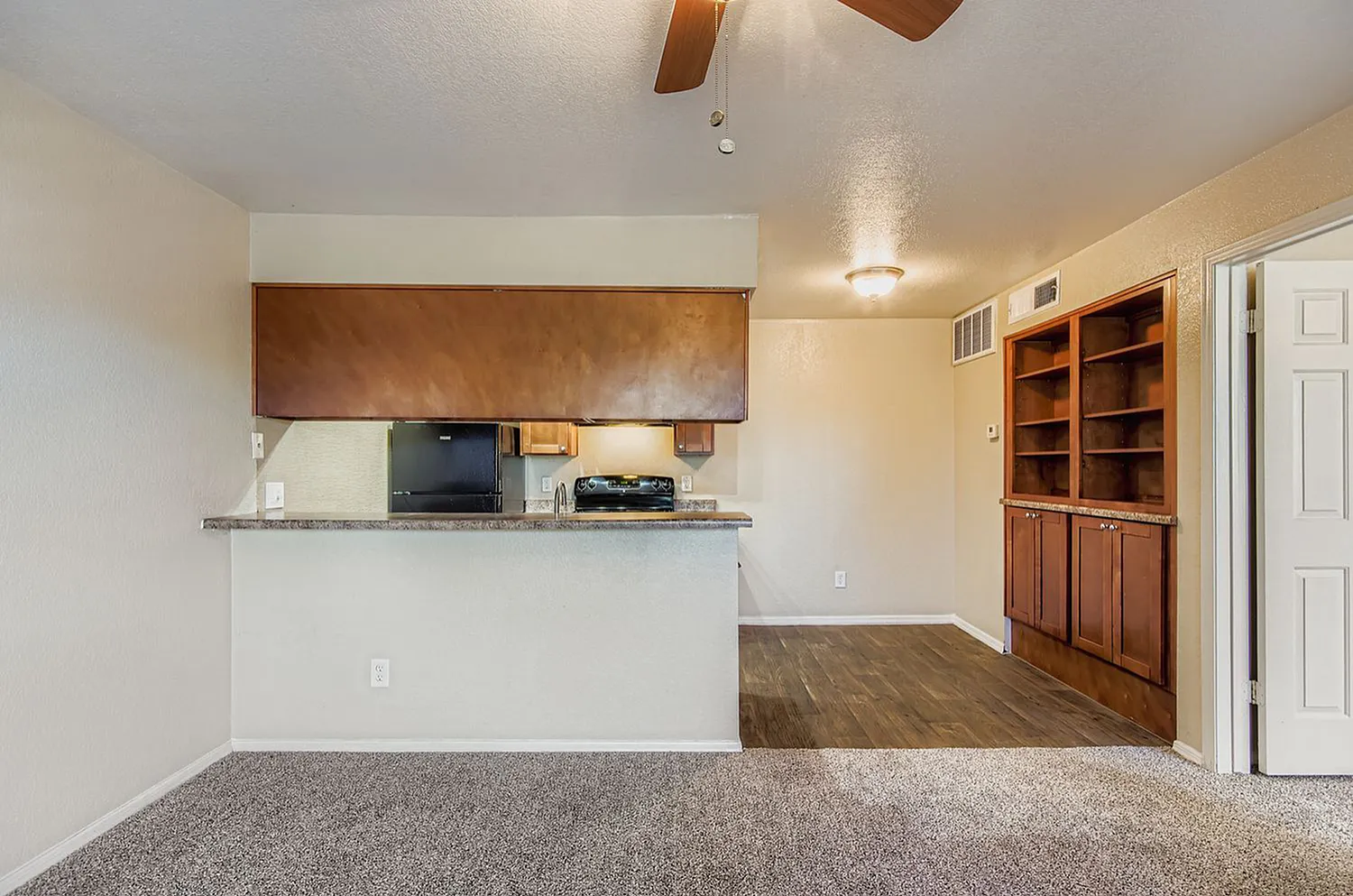 Kitchen and living space, brown cabinetry, granite countertops, wood-style plank flooring