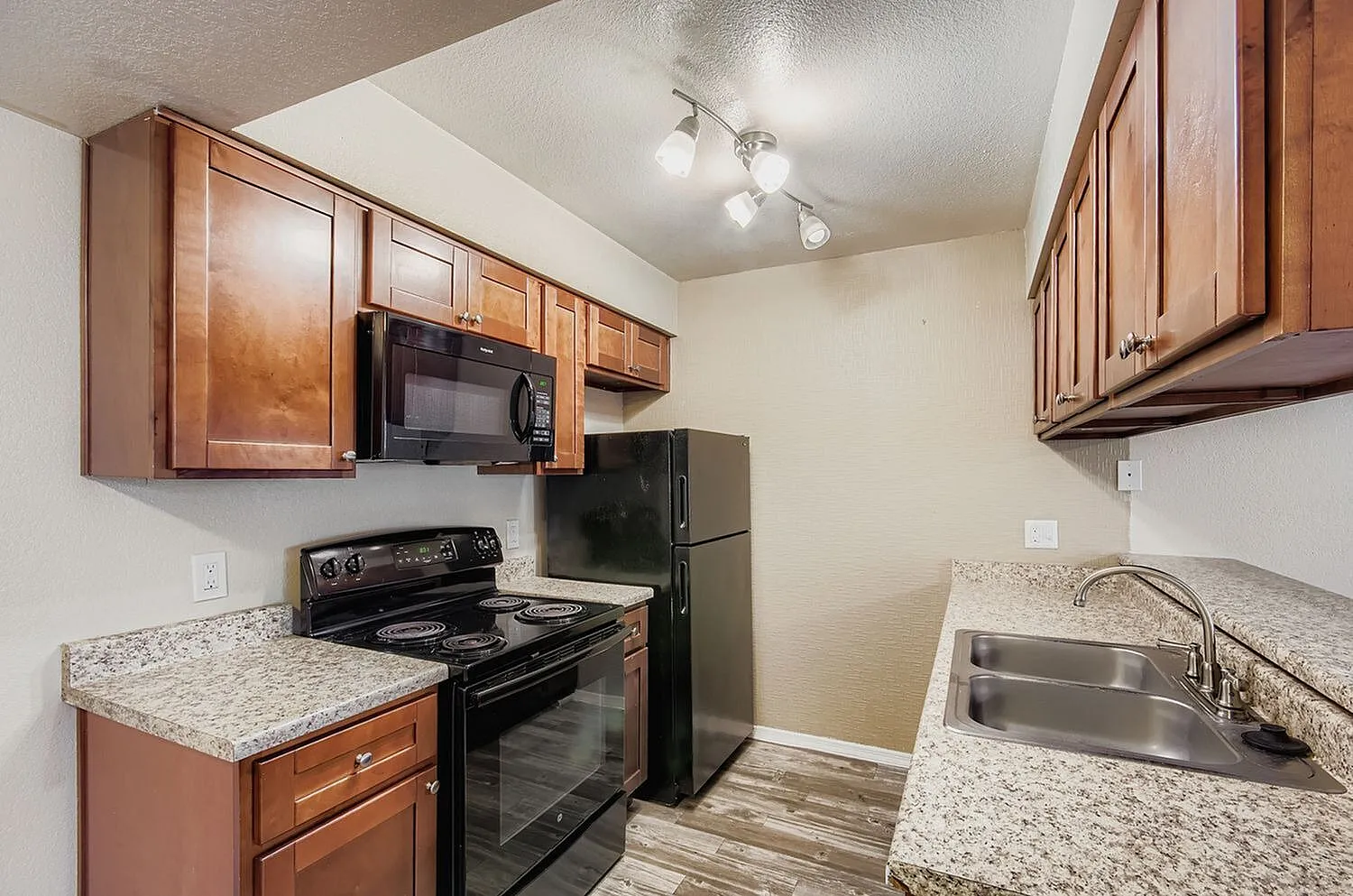 Kitchen, wood cabinetry, granite countertops, black appliances, wood-style plank flooring