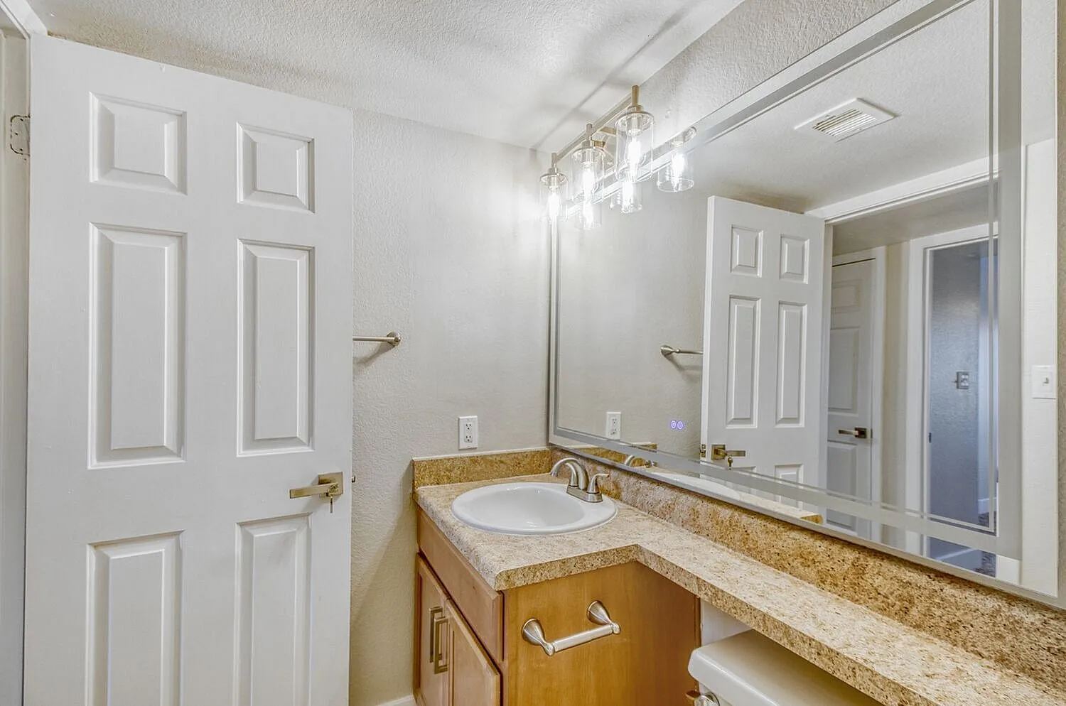 Primary bathroom, granite countertops, wood vanity cabinetry, large mirror, chrome fixtures