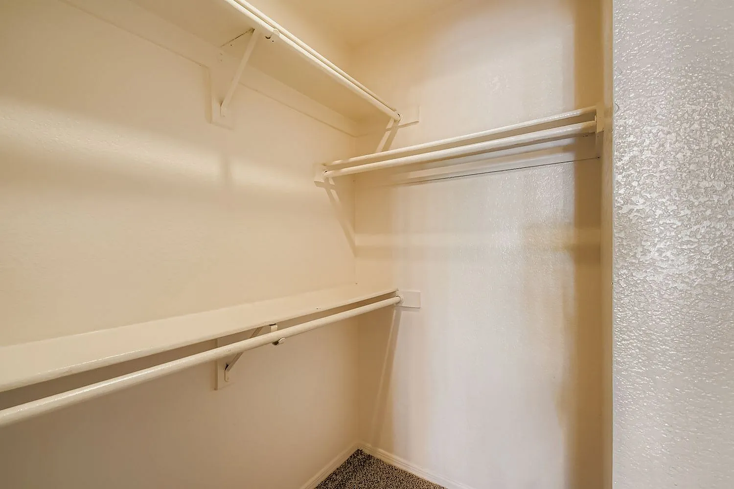 Closet, metal hanging rods, shelving, white interior, carpet flooring