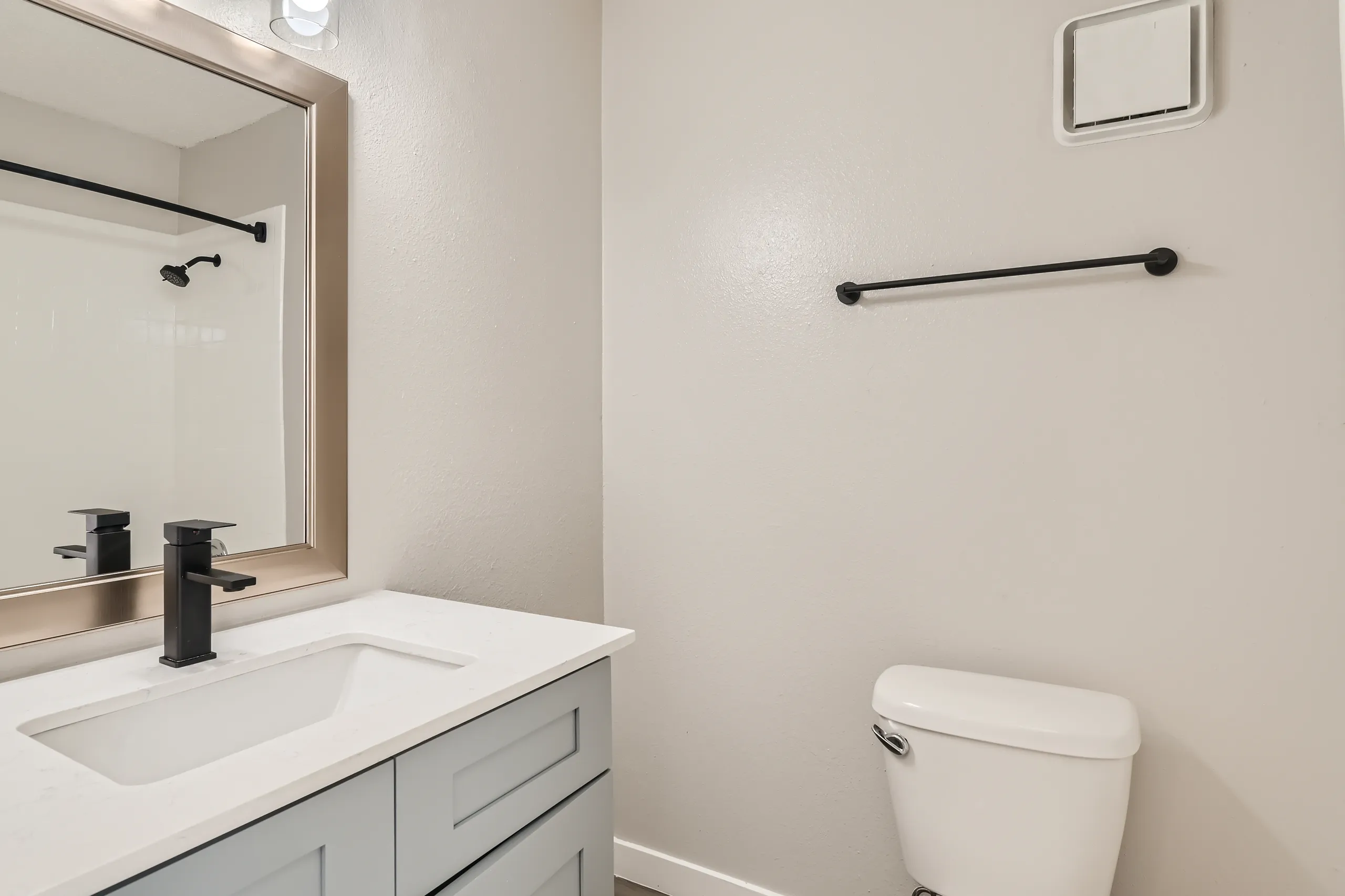 Primary bathroom with gray vanity and matte black fixtures