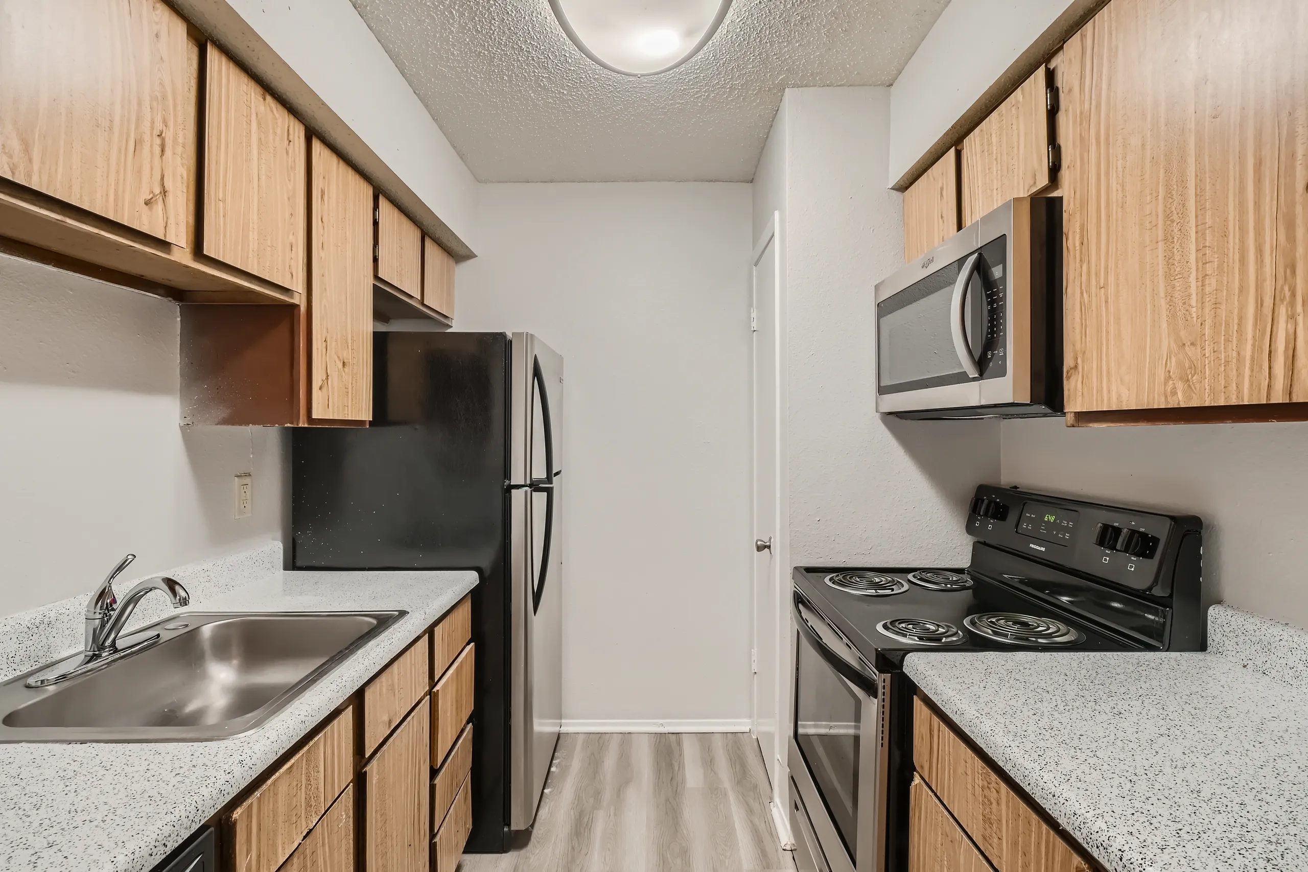 Galley kitchen with wood cabinetry and stainless refrigerator