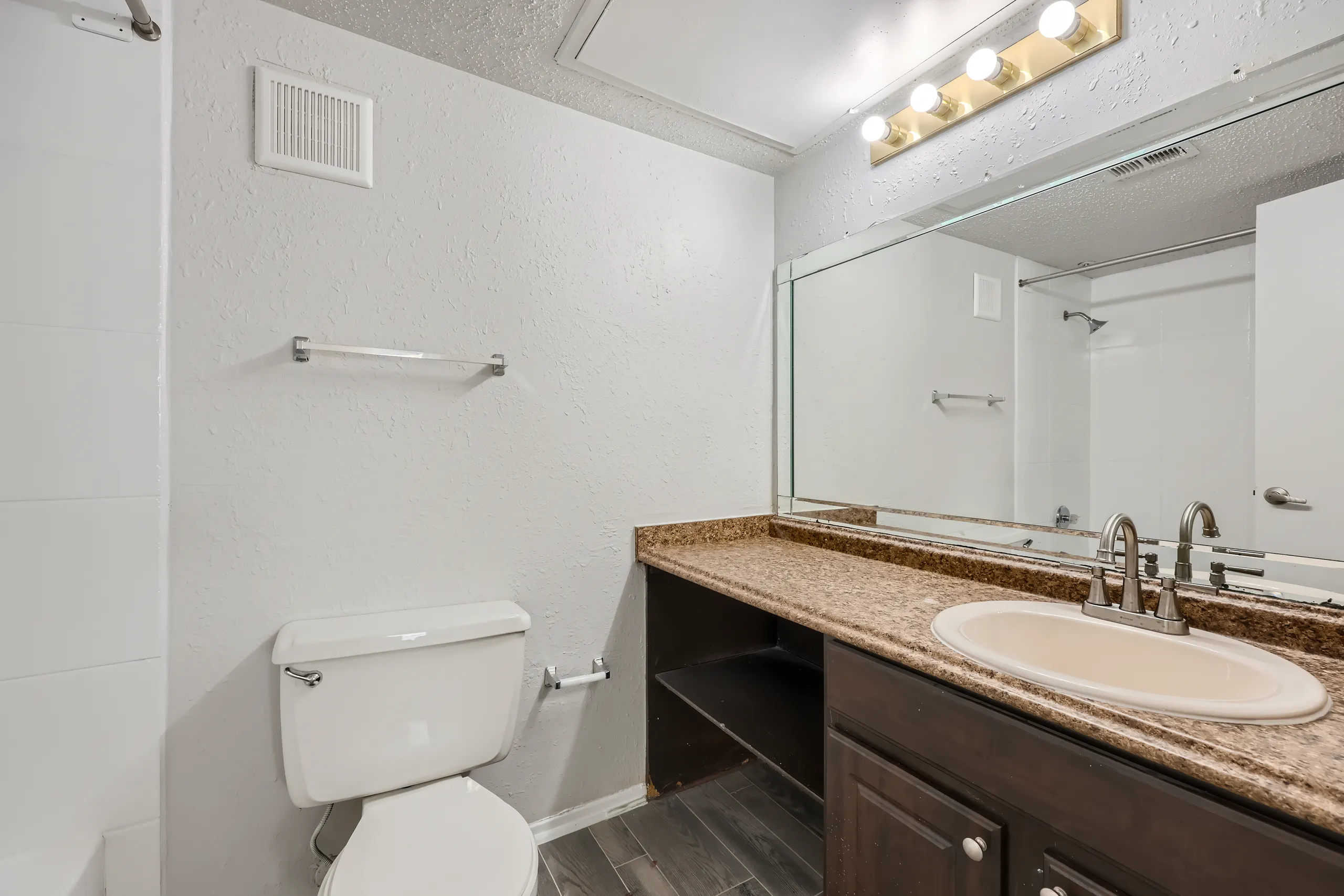 Primary bathroom with granite-style vanity and tub shower combo