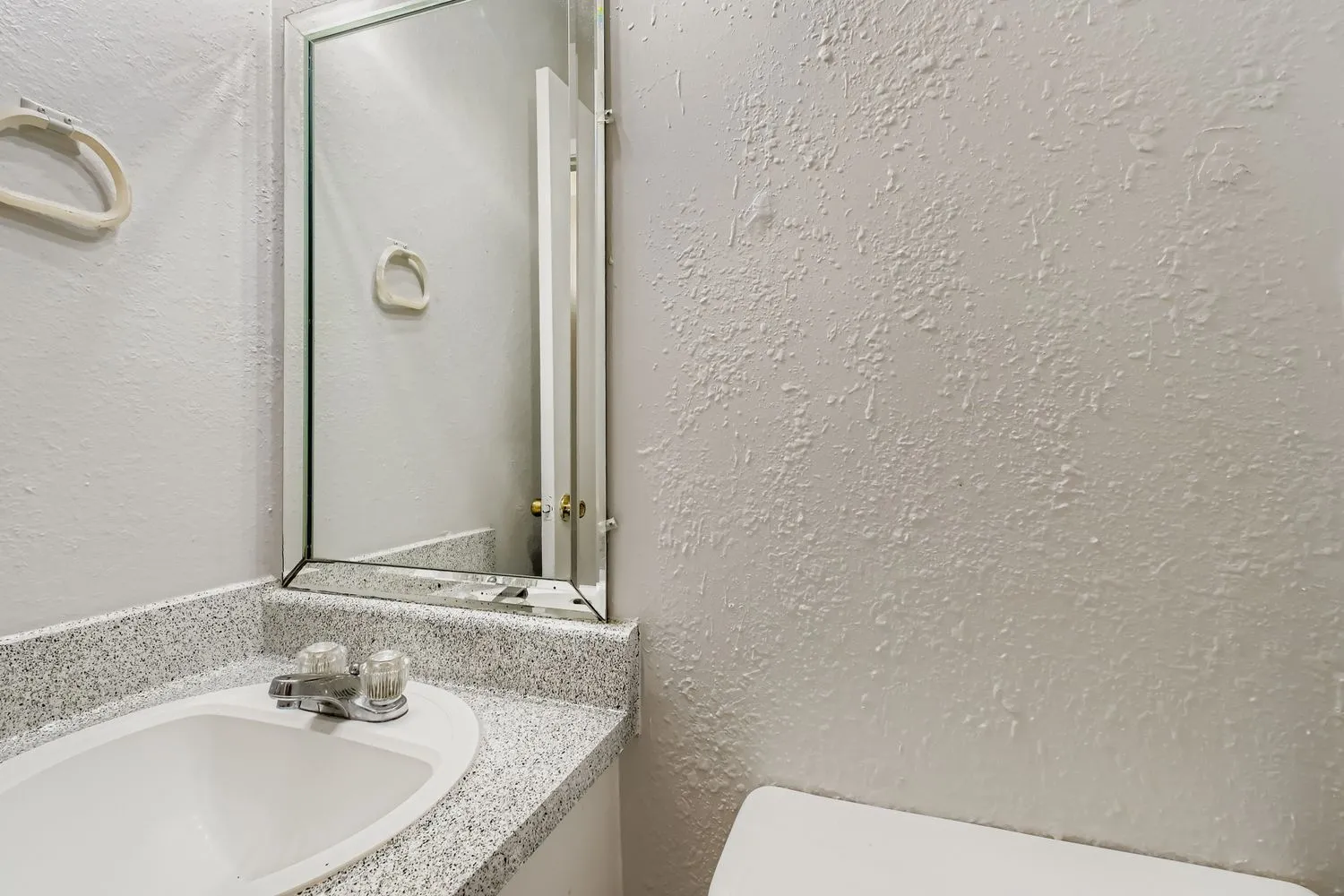 Vanity with mirror, granite countertop, textured wall finish