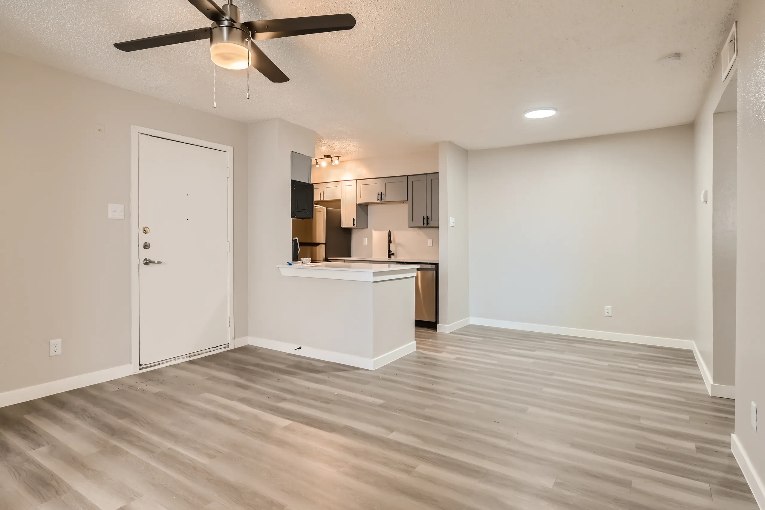 Living room with wood-style plank flooring and open kitchen view
