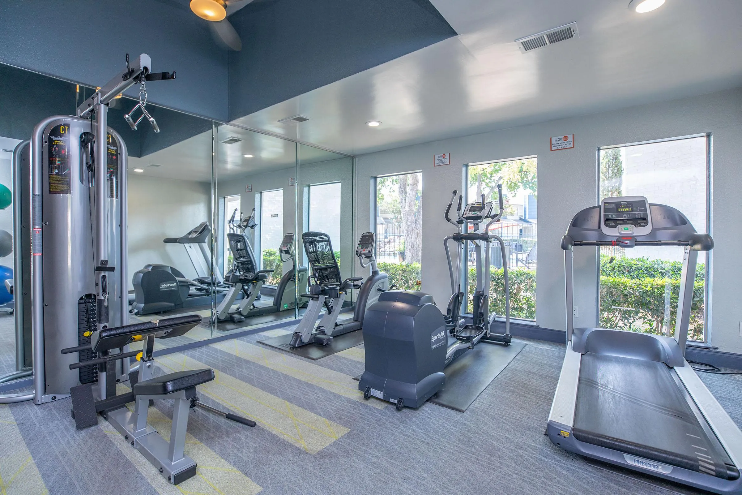 Fitness center with treadmills, elliptical, mirrored wall, courtyard view