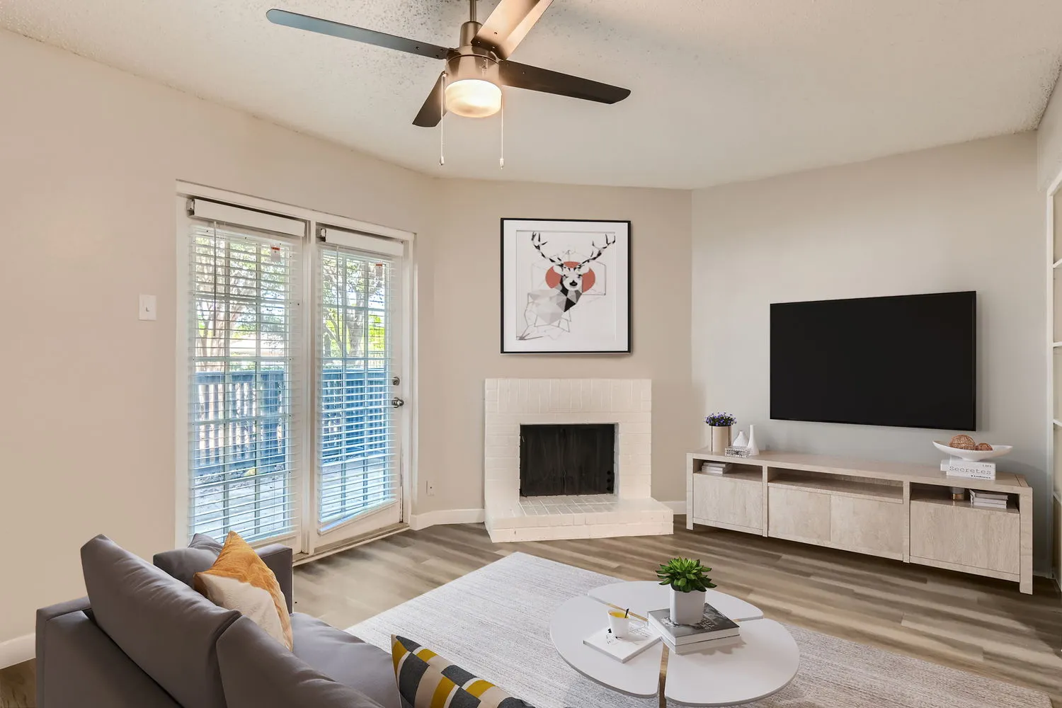 Staged living room, brick fireplace, wood-style flooring, sliding glass door