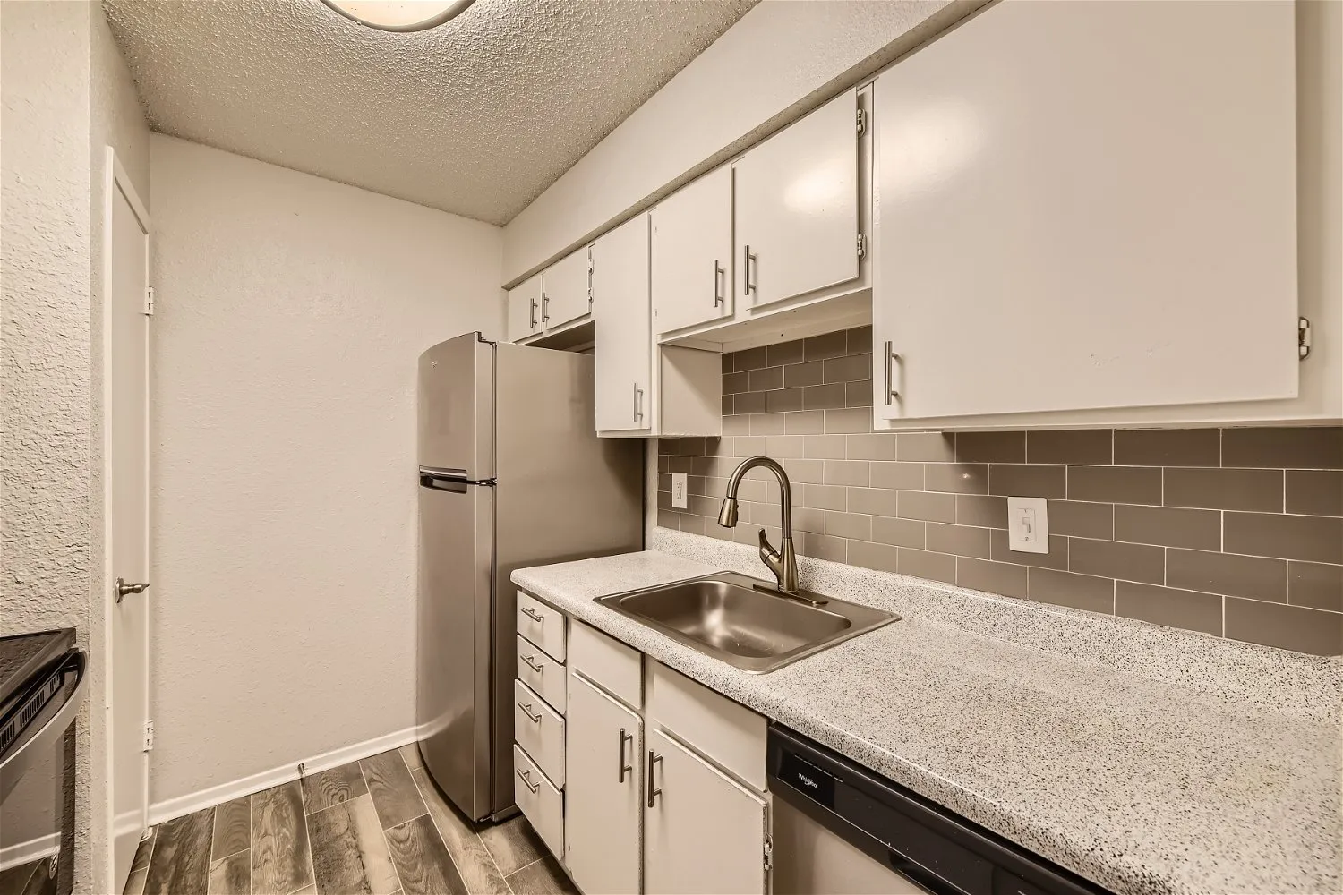 Galley kitchen with white cabinetry and subway tile backsplash