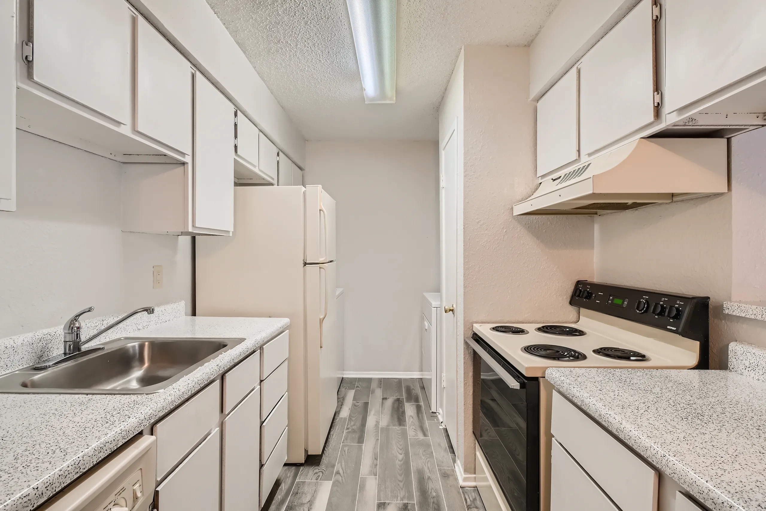 Galley kitchen with white cabinetry and speckled countertops