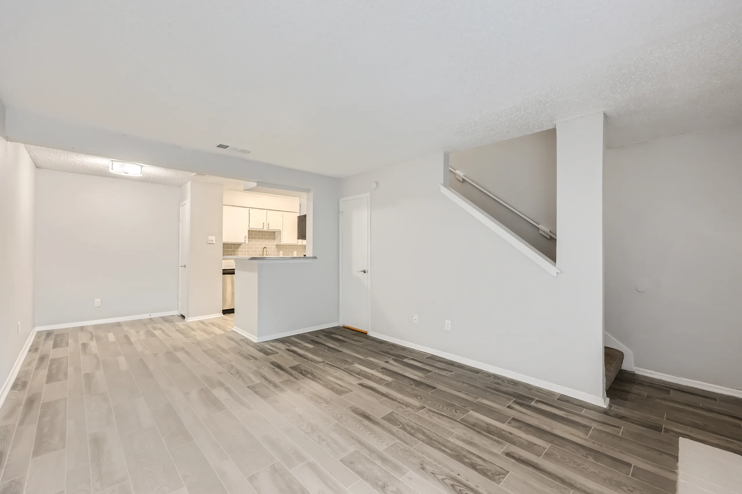 Living room with wood-style plank flooring and open kitchen view