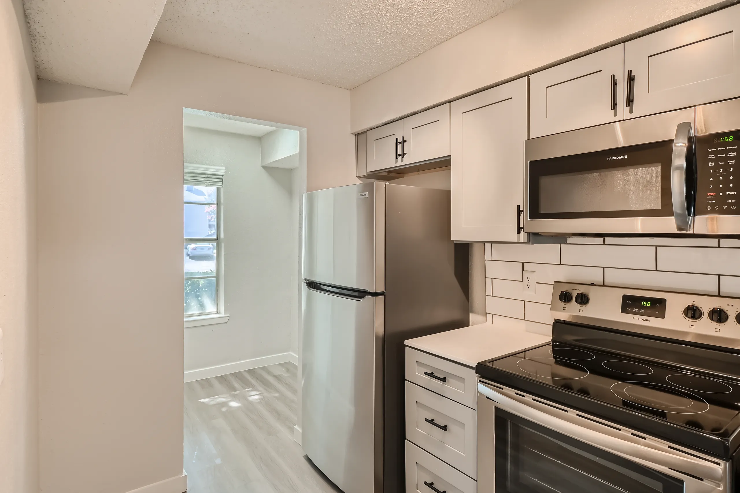 Kitchen with white cabinetry, subway tile backsplash, and stainless refrigerator