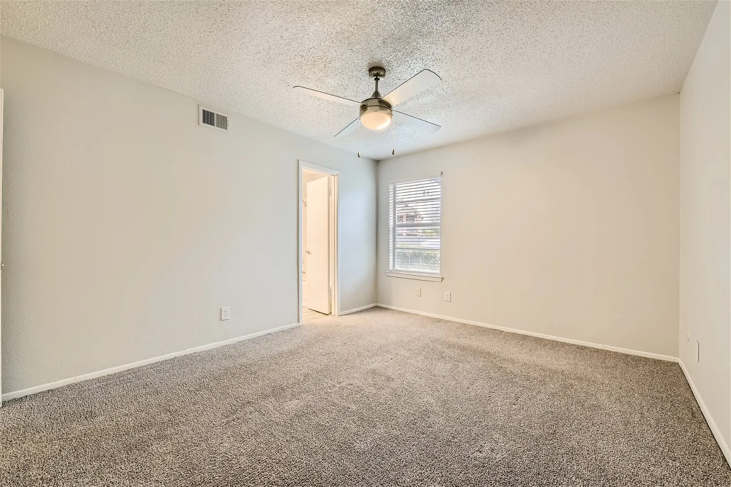 Primary bedroom with plush carpet and ensuite access