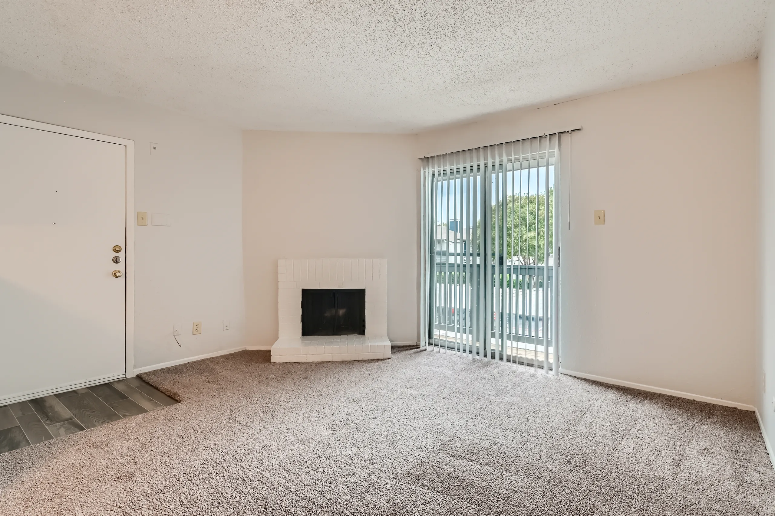 Living room with brick fireplace and sliding glass door to balcony