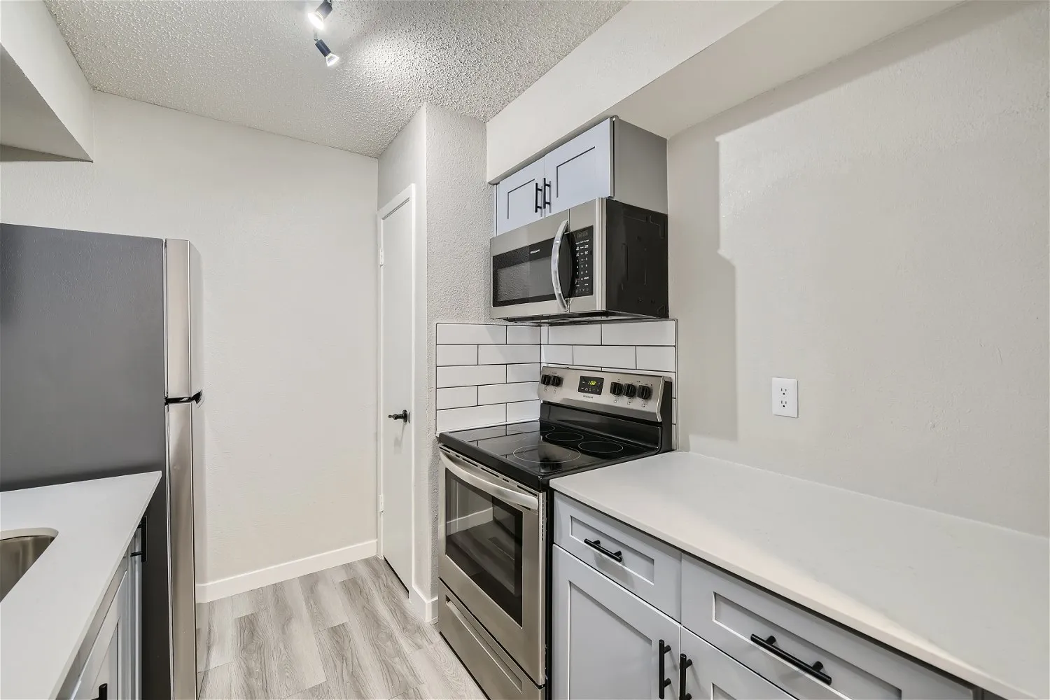 Kitchen with gray cabinetry, subway tile backsplash, and stainless appliances
