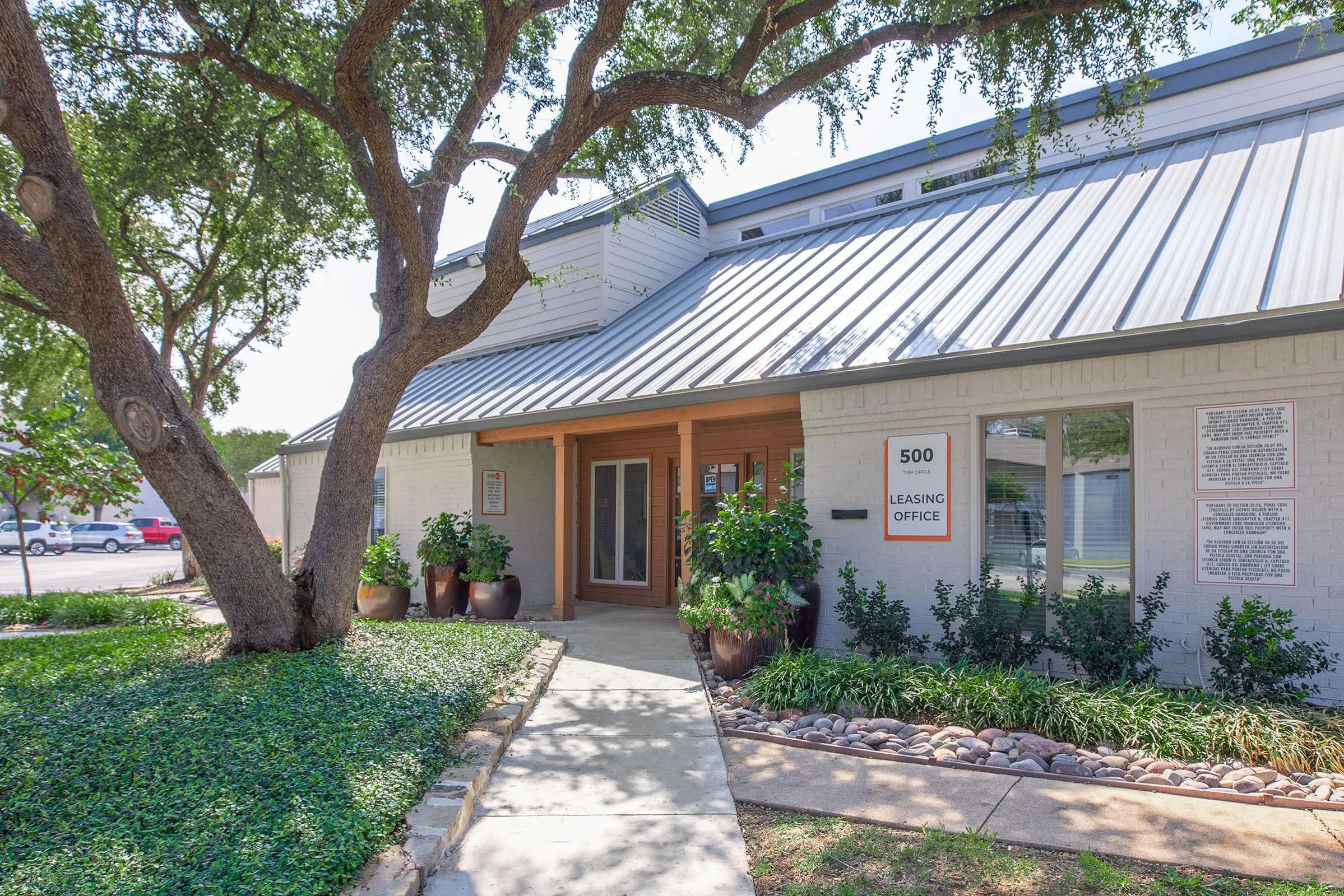 Leasing office entrance, brick and wood exterior, standing seam metal roof, oak tree canopy
