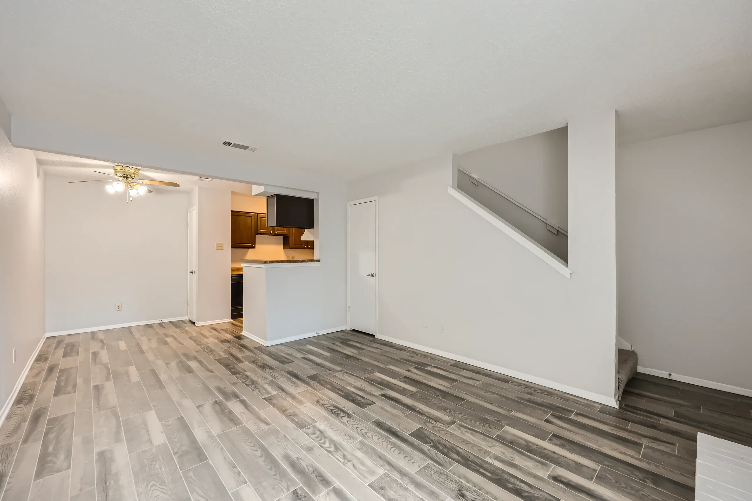 Living room with wood-style plank flooring and open kitchen view