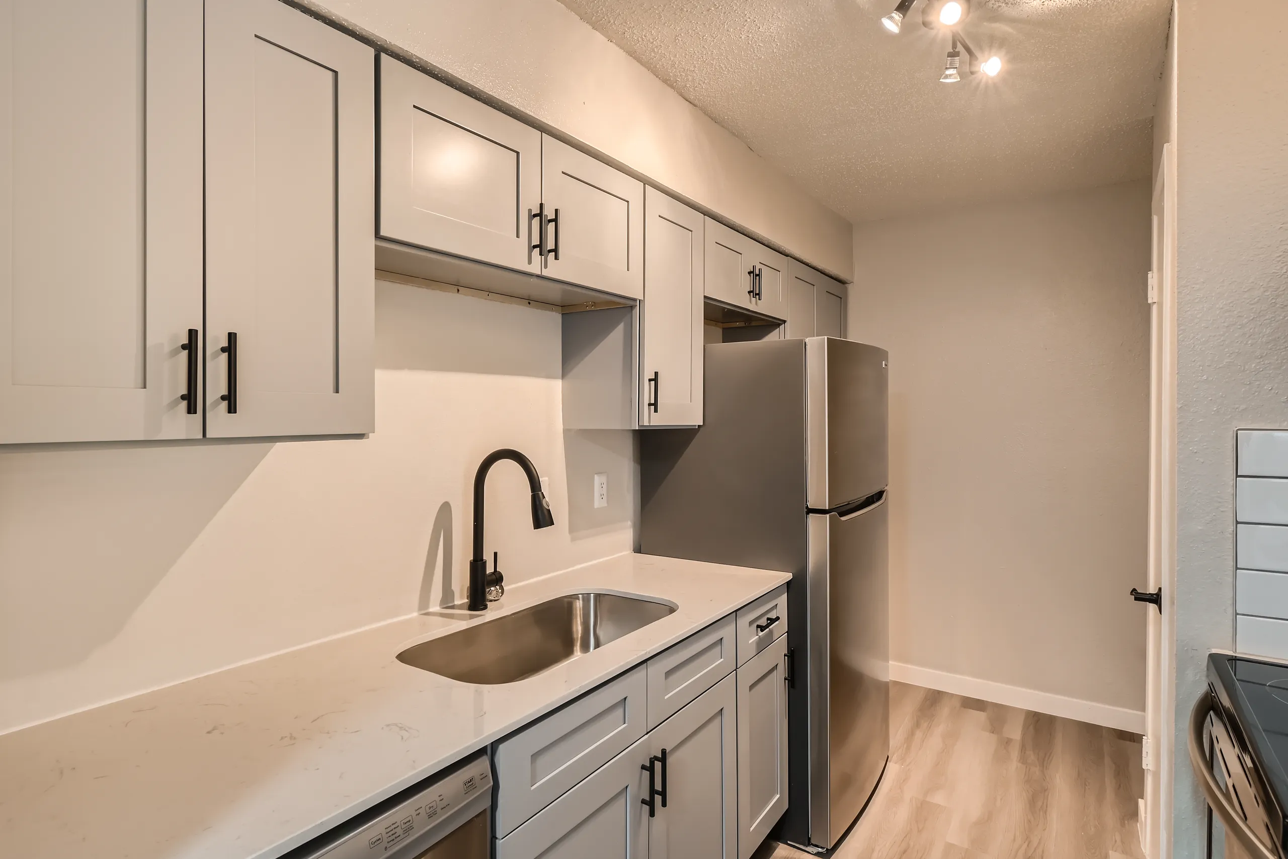 Galley kitchen with gray cabinetry and stainless refrigerator
