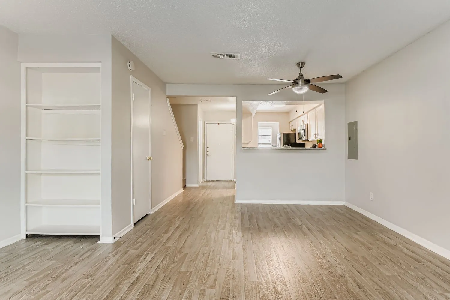 Open living area, built-in shelving, ceiling fan, pass-through to kitchen
