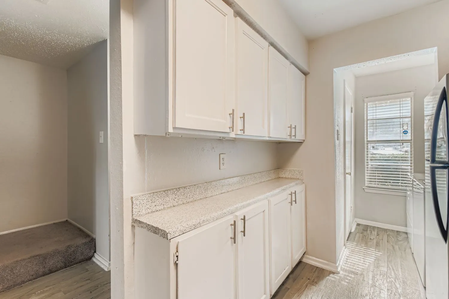 Cabinetry and counter space near laundry nook, natural light from window