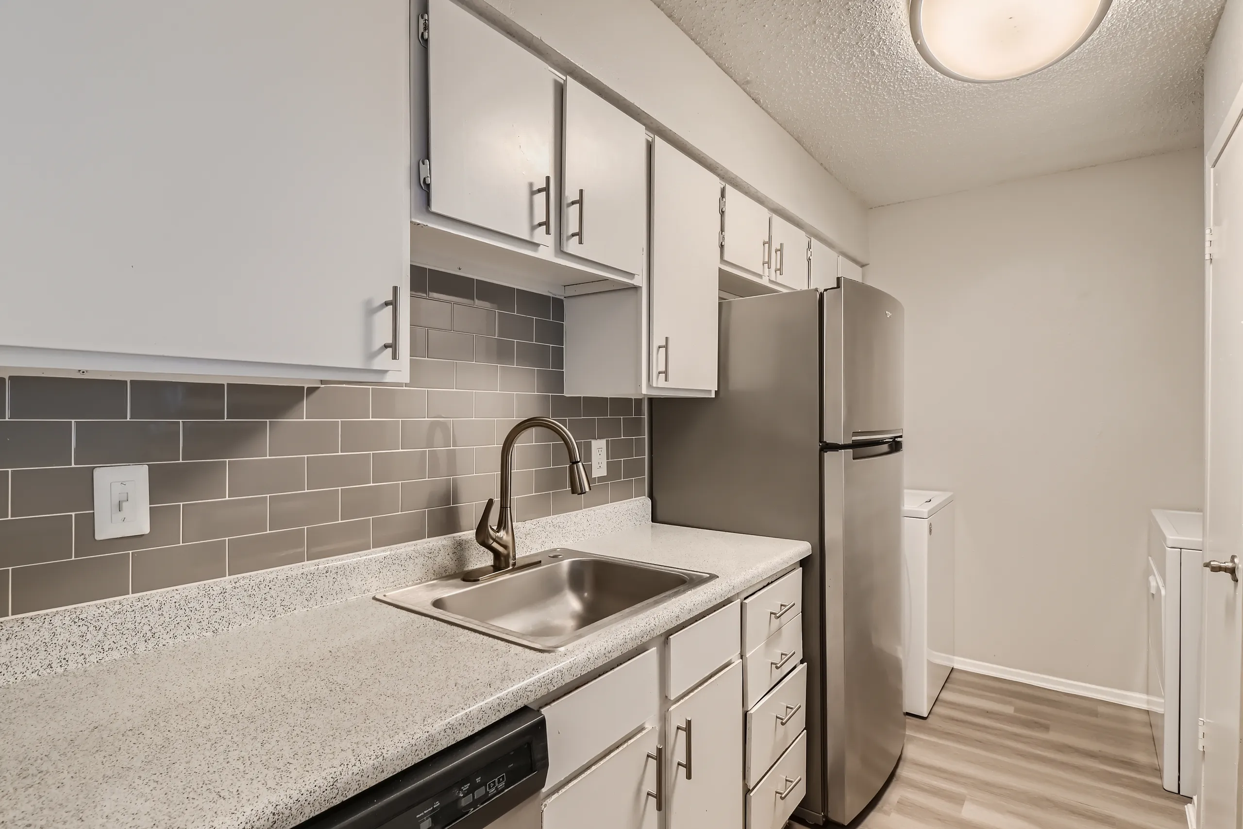 Kitchen with white cabinetry, subway tile backsplash, and stainless refrigerator