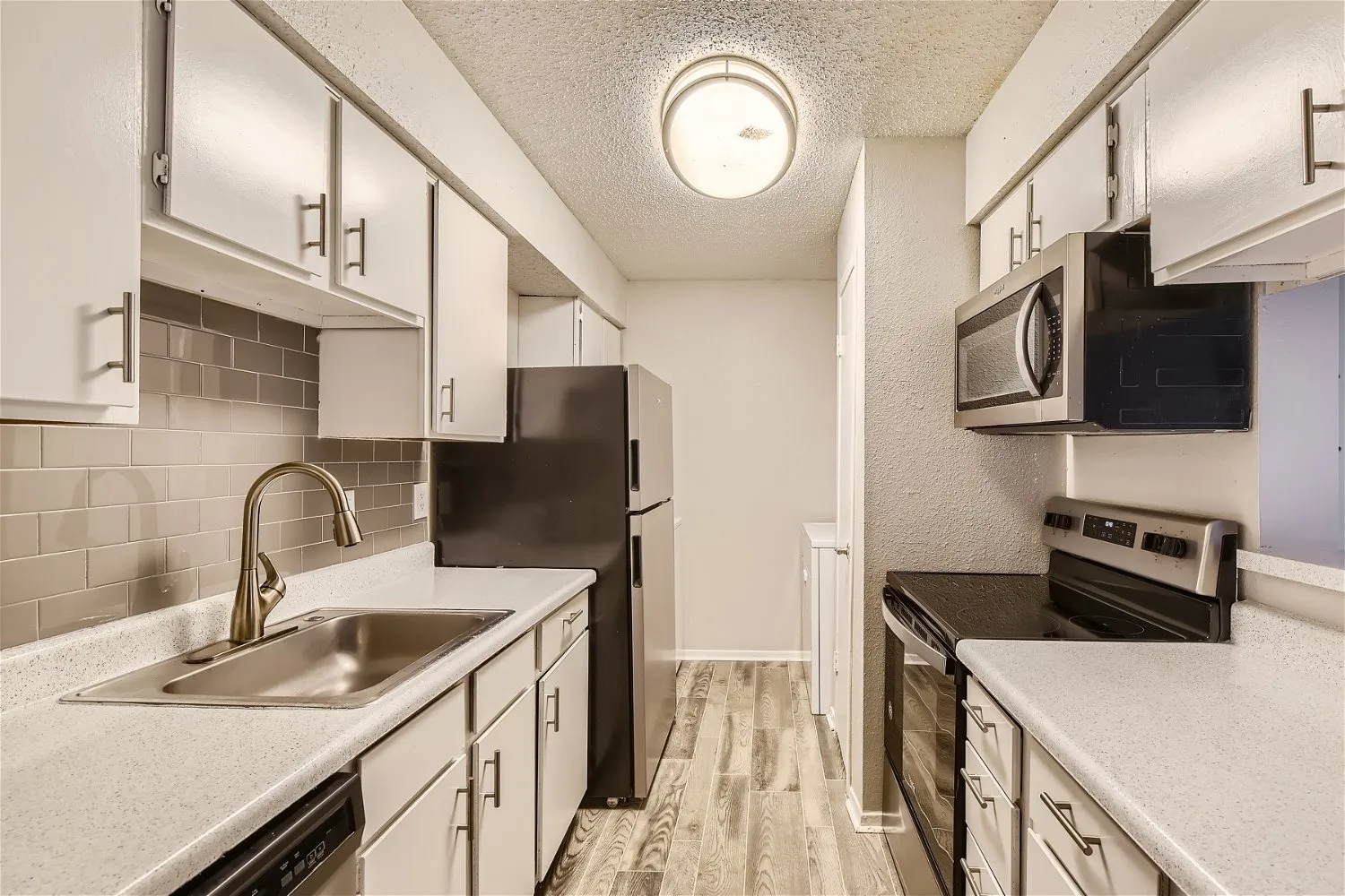 Galley kitchen with white cabinetry and subway tile backsplash