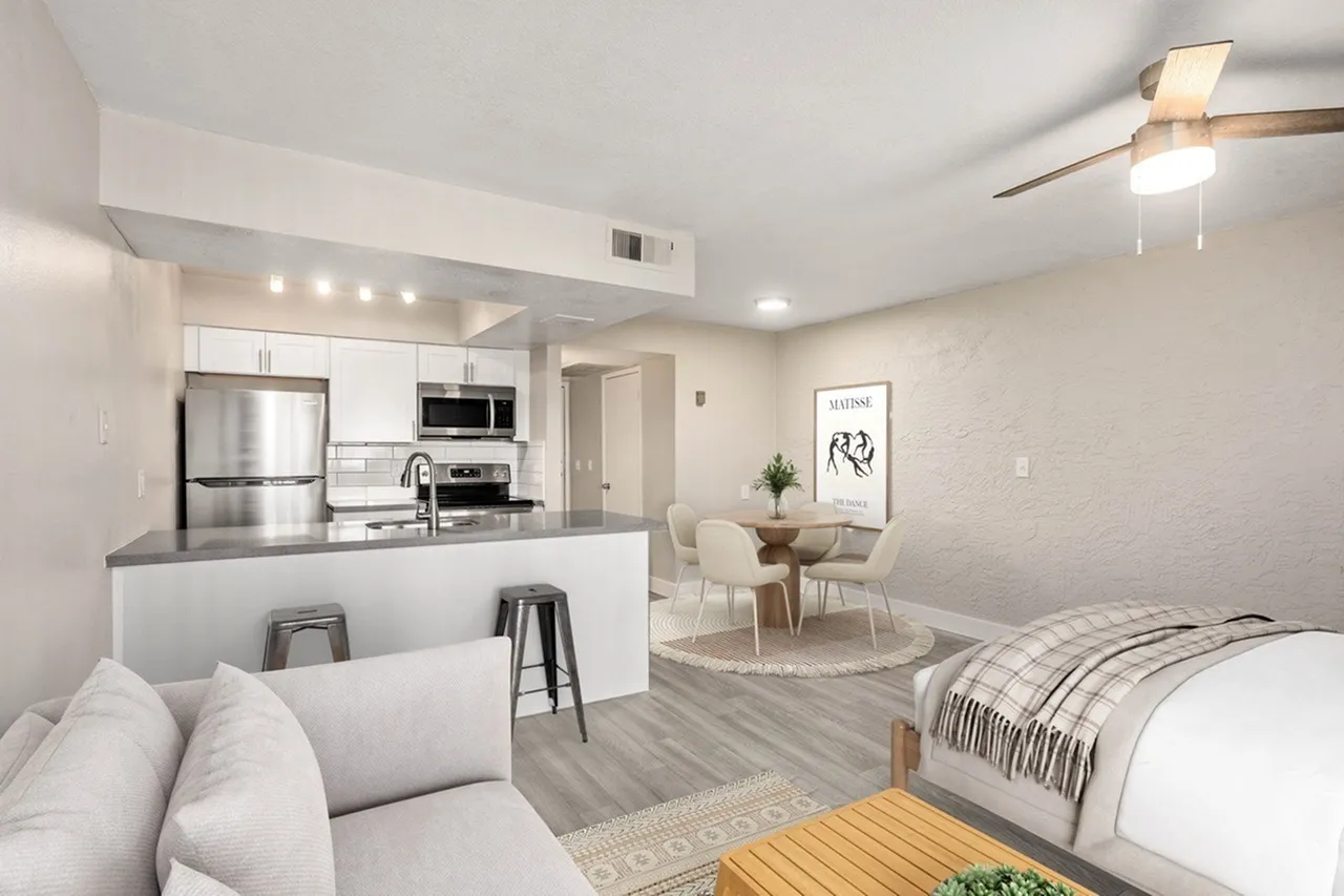 Studio apartment, wood-style plank flooring, white cabinetry, stainless appliances, ceiling fan