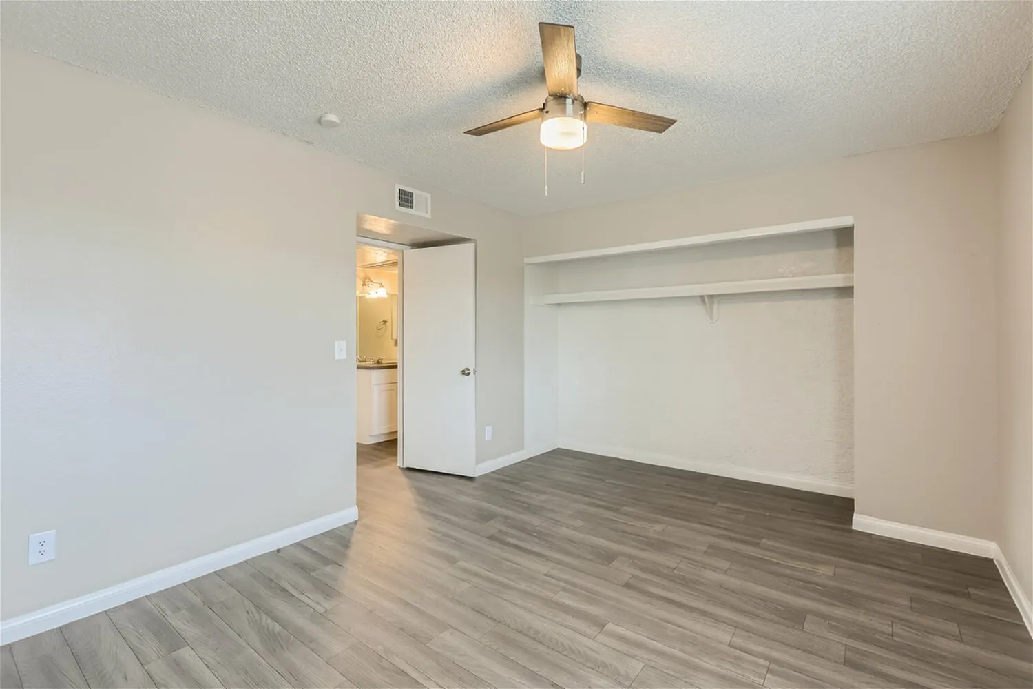 Bedroom, wood-style plank flooring, ceiling fan with light, large walk-in closet