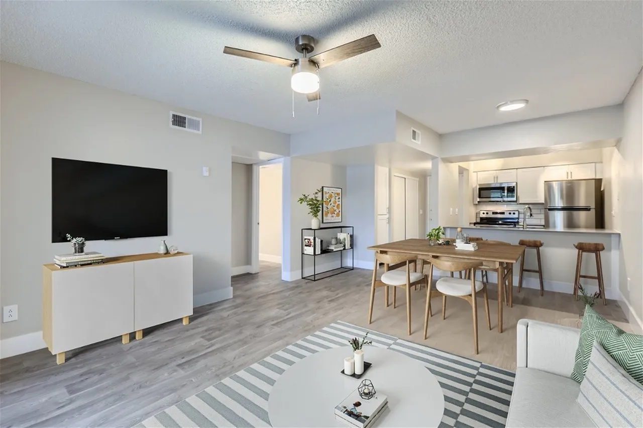 Open concept living room and kitchen, wood-style plank flooring, ceiling fan, stainless appliances