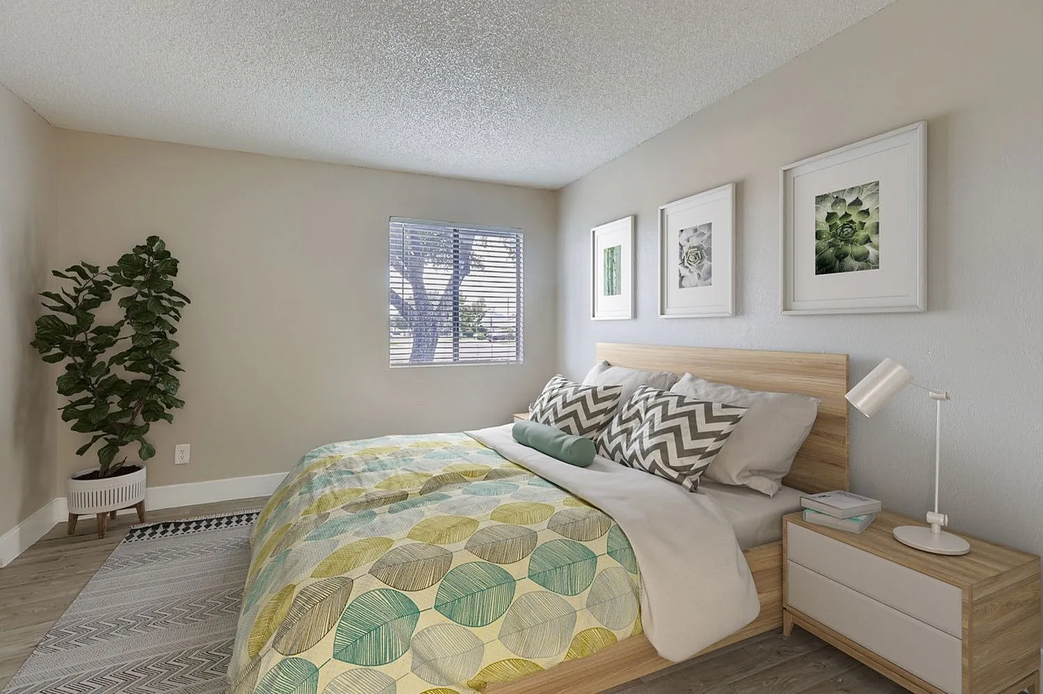 Primary bedroom, wood-style plank flooring, light wood platform bed, patterned throw pillows, framed botanical artwork, potted plant, shuttered window
