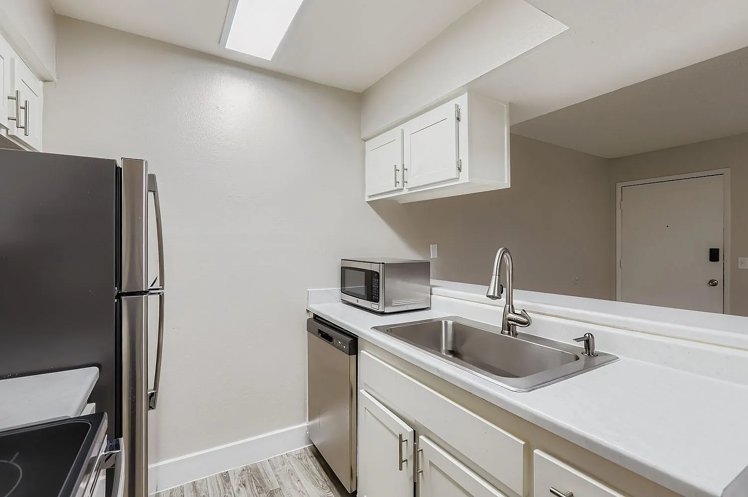 Kitchen, white cabinetry, stainless steel appliances, quartz countertops, wood-style plank flooring