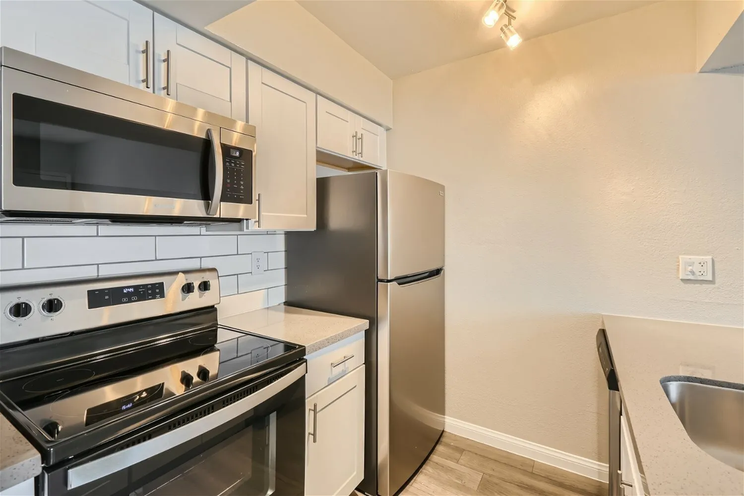 Kitchen, white shaker cabinetry, stainless steel appliances, subway tile backsplash, wood-style plank flooring