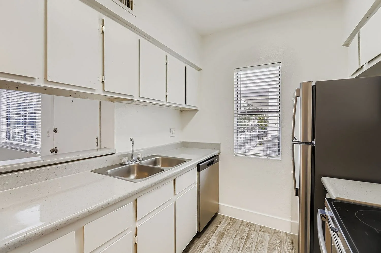Kitchen, white shaker cabinetry, quartz countertops, stainless appliances, wood-style plank flooring