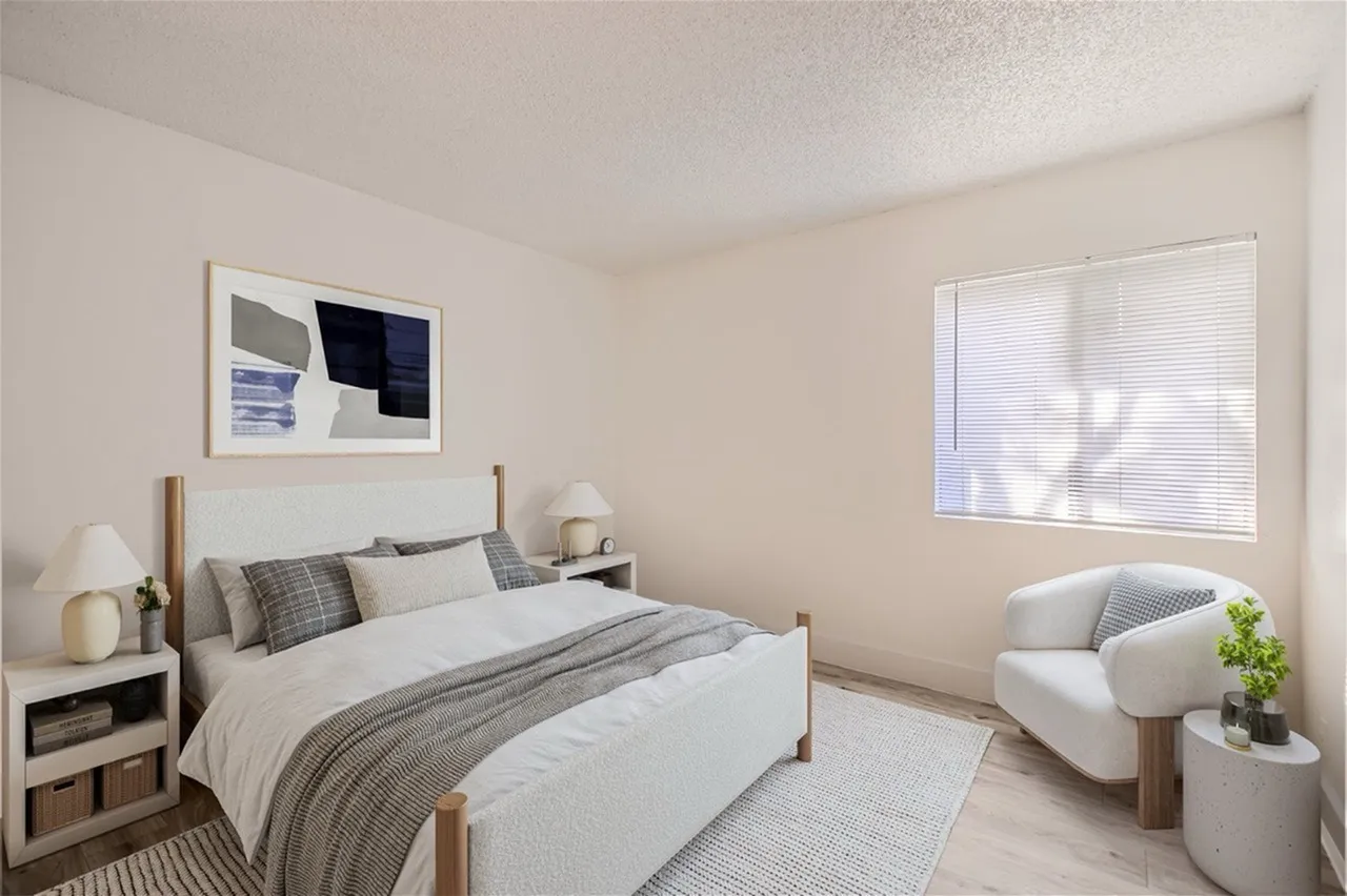 Primary bedroom, wood-style plank flooring, upholstered accent chair, natural lighting