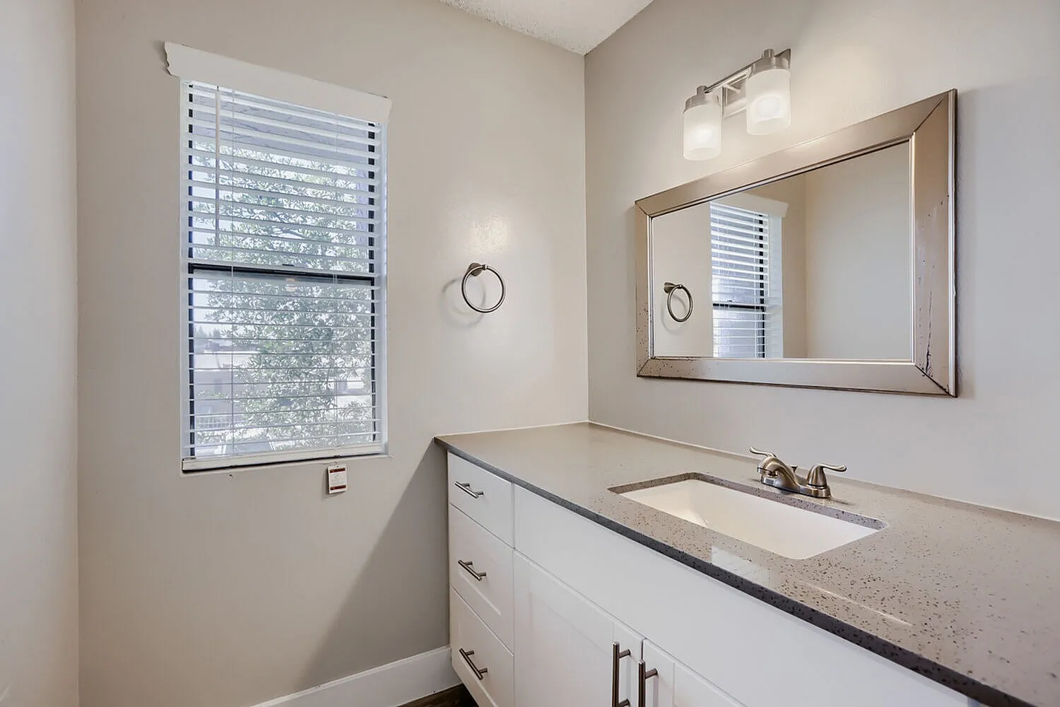 Bathroom, white vanity cabinetry, quartz countertop, framed mirror, window with blinds