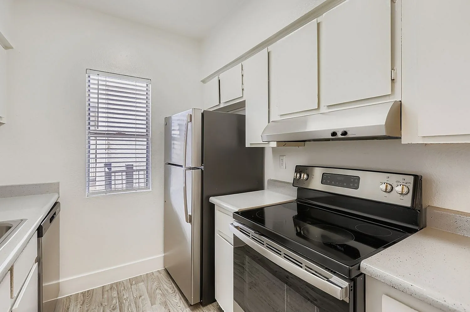 Kitchen, white shaker cabinetry, stainless appliances, quartz countertops, wood-style plank flooring