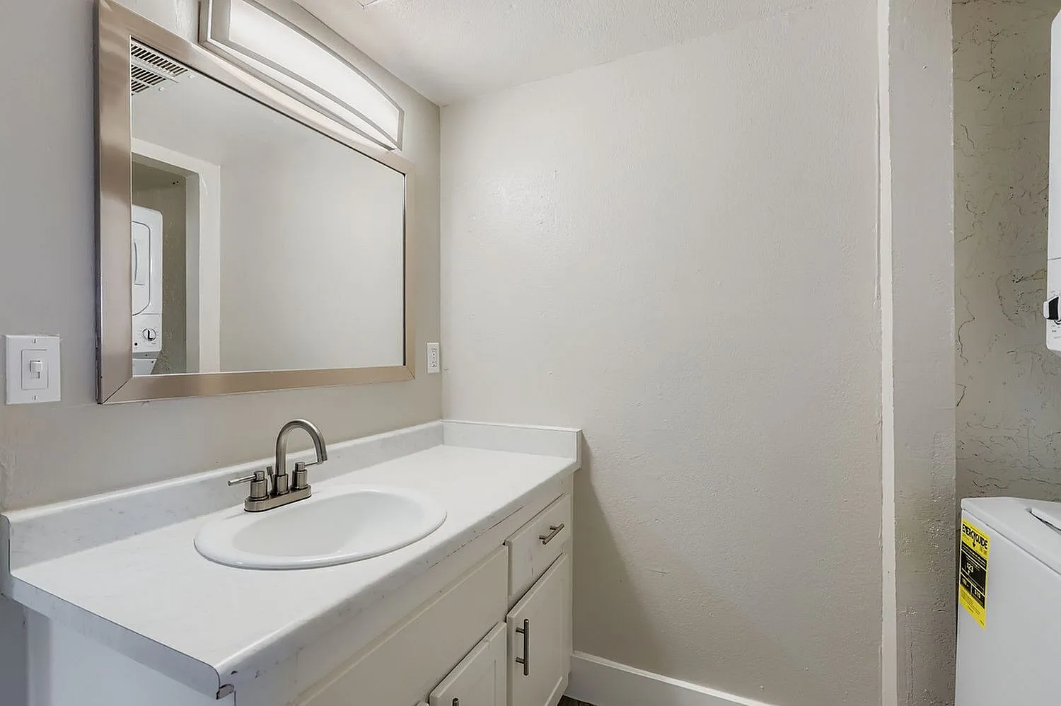 Bathroom, white vanity cabinet, round sink, framed mirror with lighting, white walls