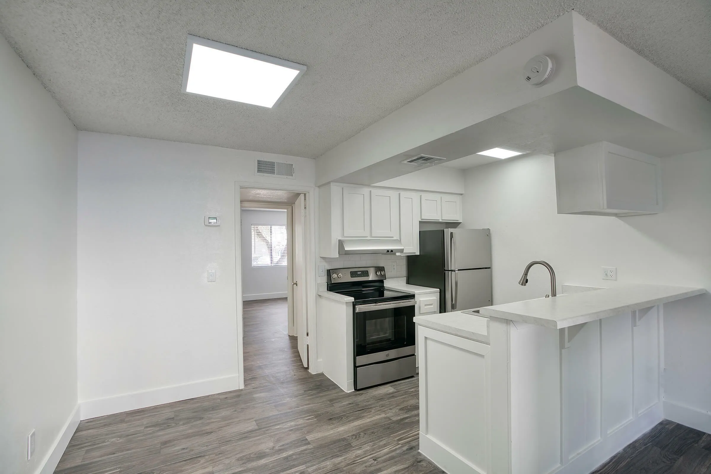 Kitchen, white shaker cabinetry, stainless appliances, white countertops, wood-style plank flooring