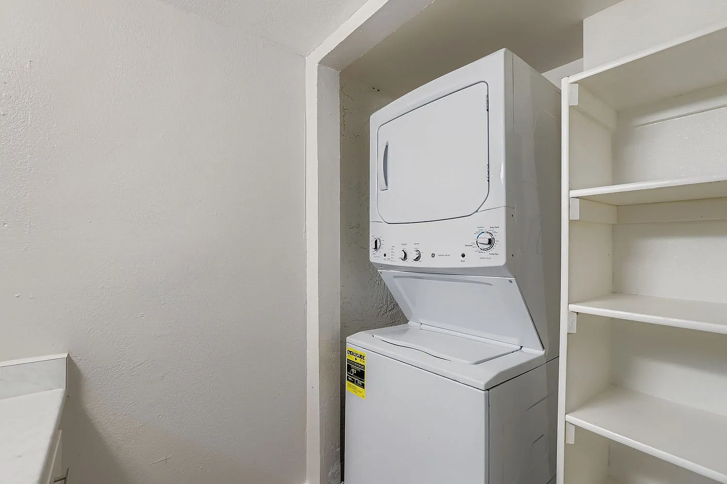 Laundry closet, stacked washer and dryer, white appliances, shelving