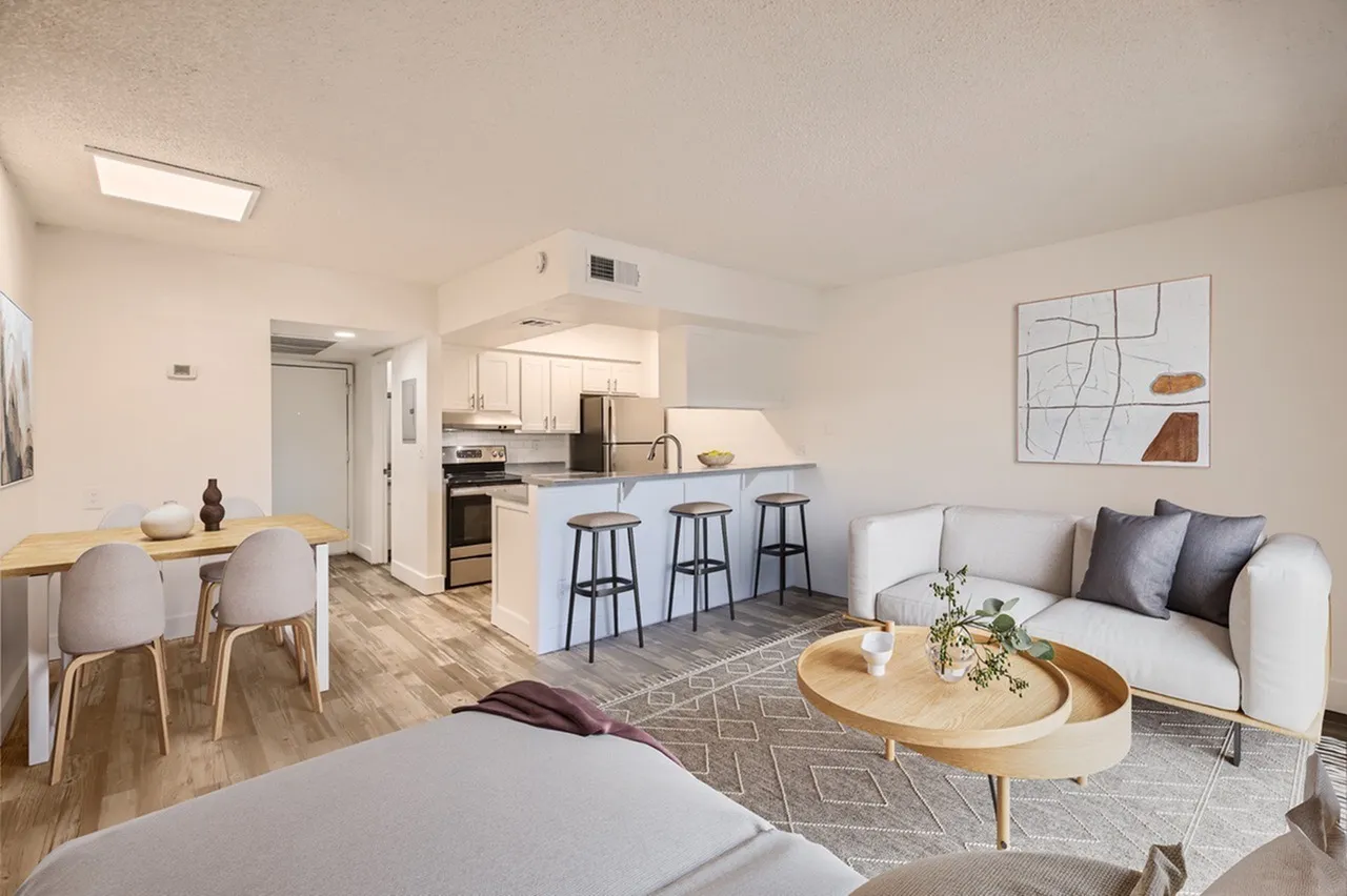 Open concept living area, white cabinetry, kitchen island with bar seating, wood-style plank flooring