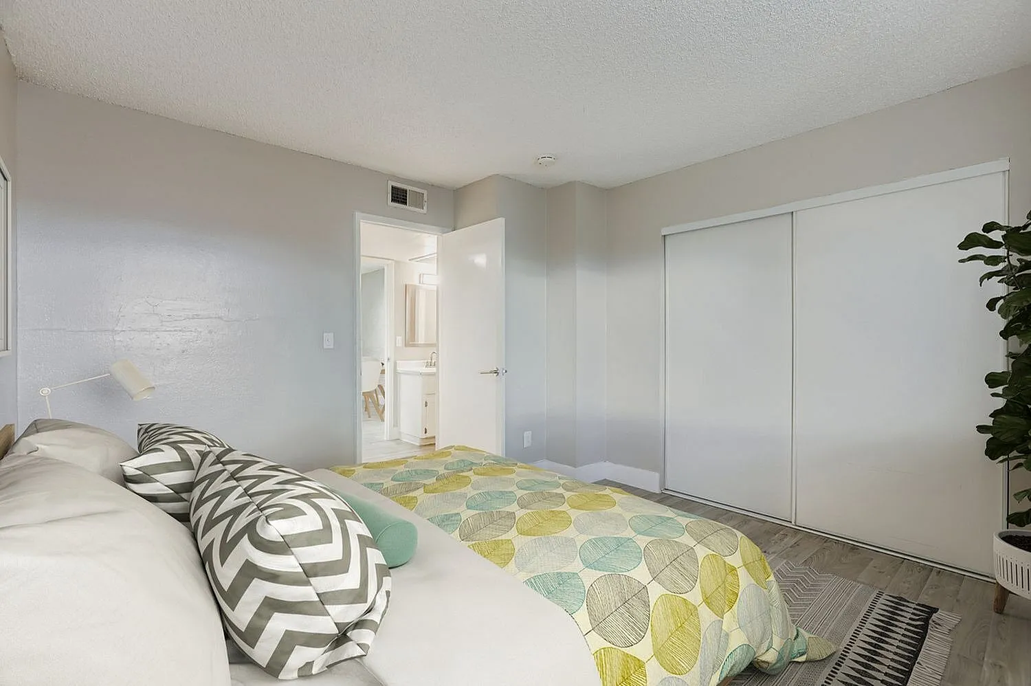 Primary bedroom, wood-style plank flooring, glass closet doors, geometric bedding