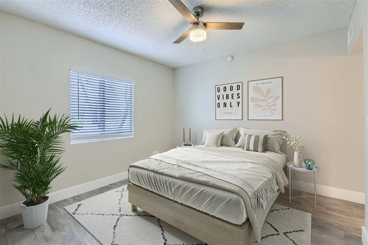 Primary bedroom, wood-style plank flooring, ceiling fan, upholstered bed, geometric area rug