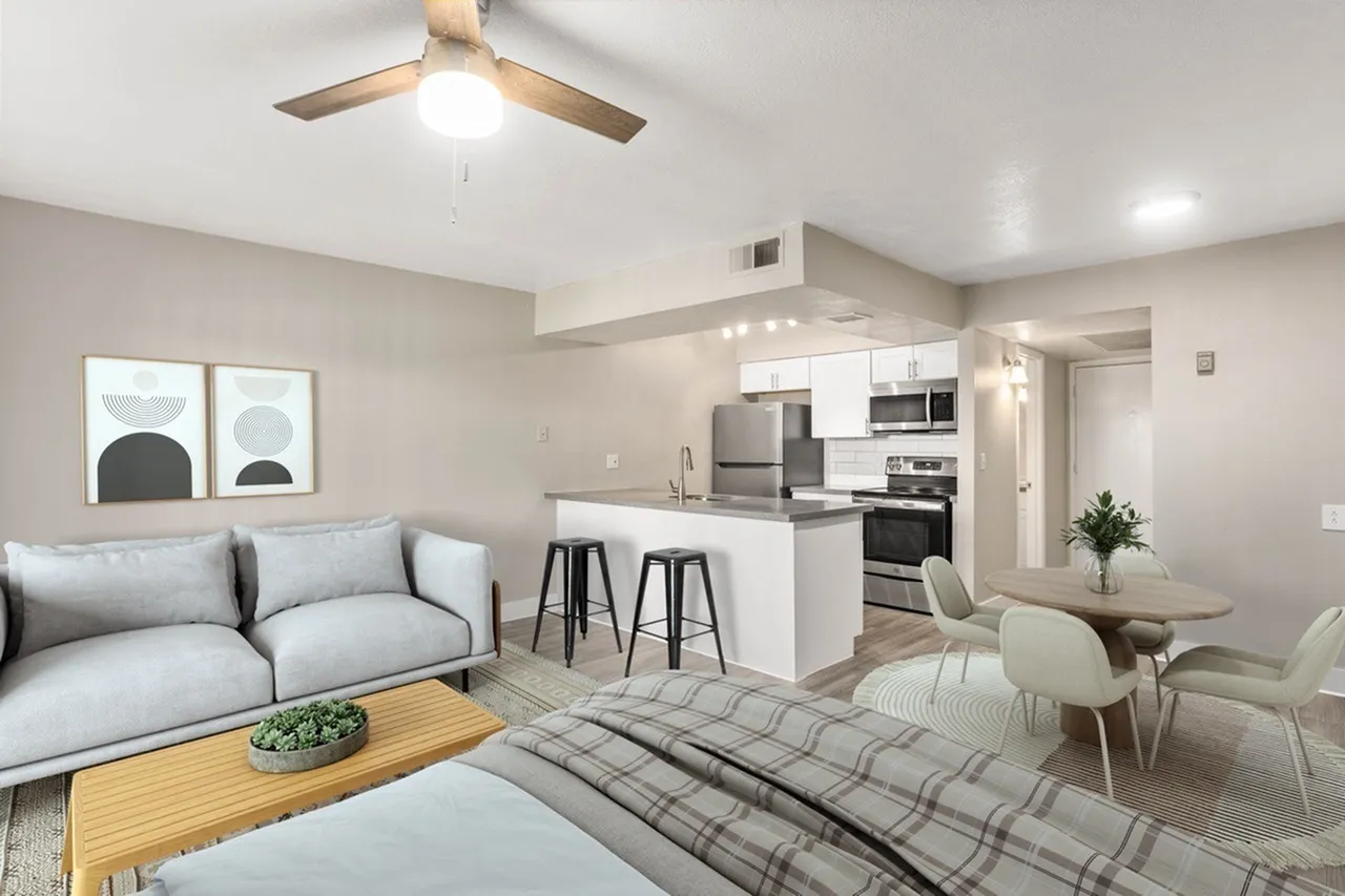 Open concept living room and kitchen, wood-style plank flooring, white kitchen island, stainless appliances, ceiling fan